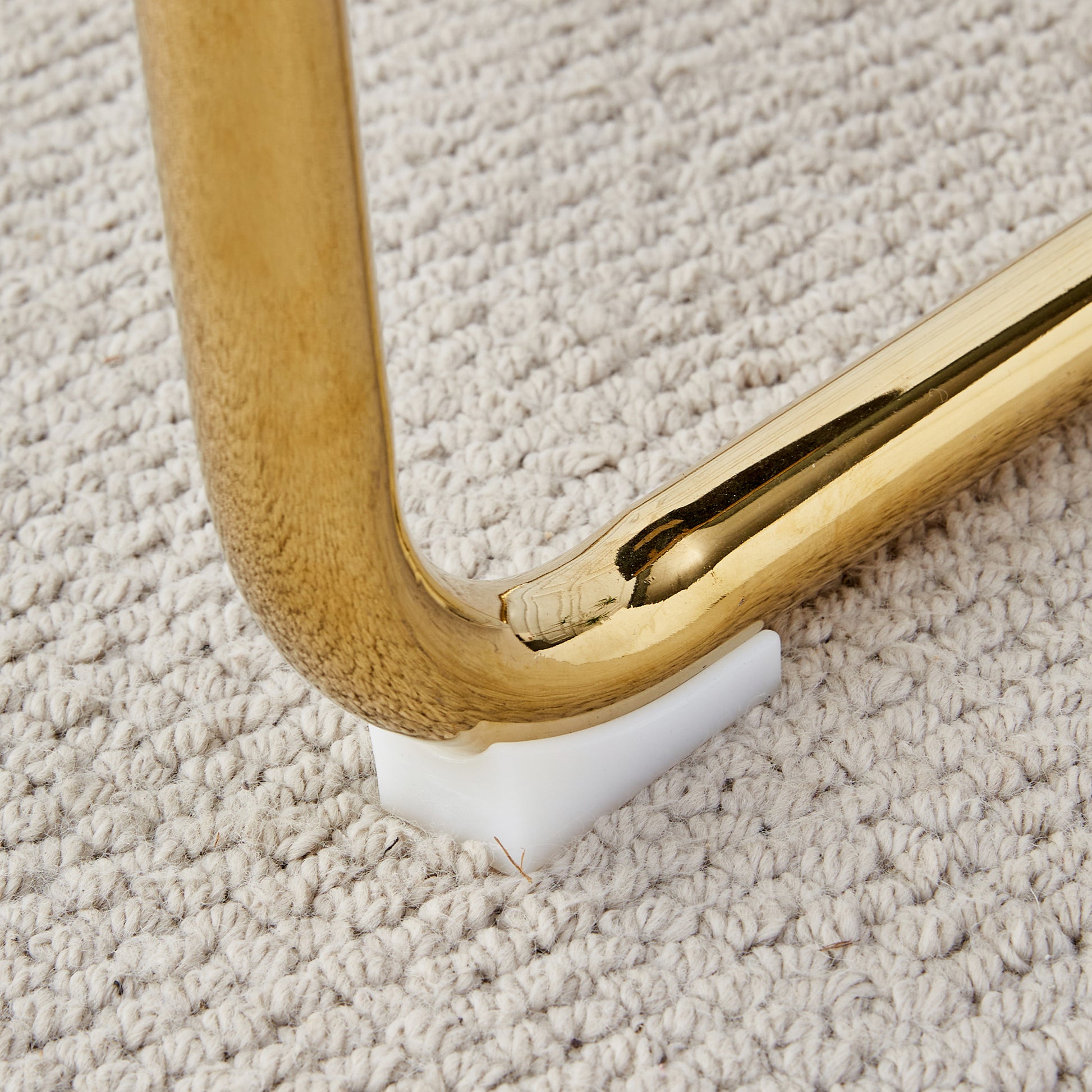 Shiny brass furniture leg detail on textured rug