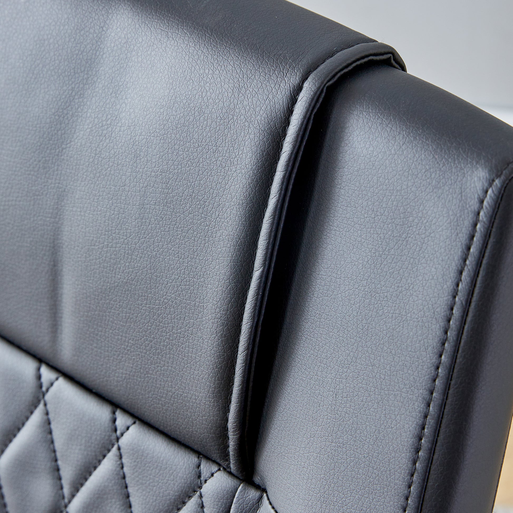 Black faux leather office chair backrest detail with diamond stitching