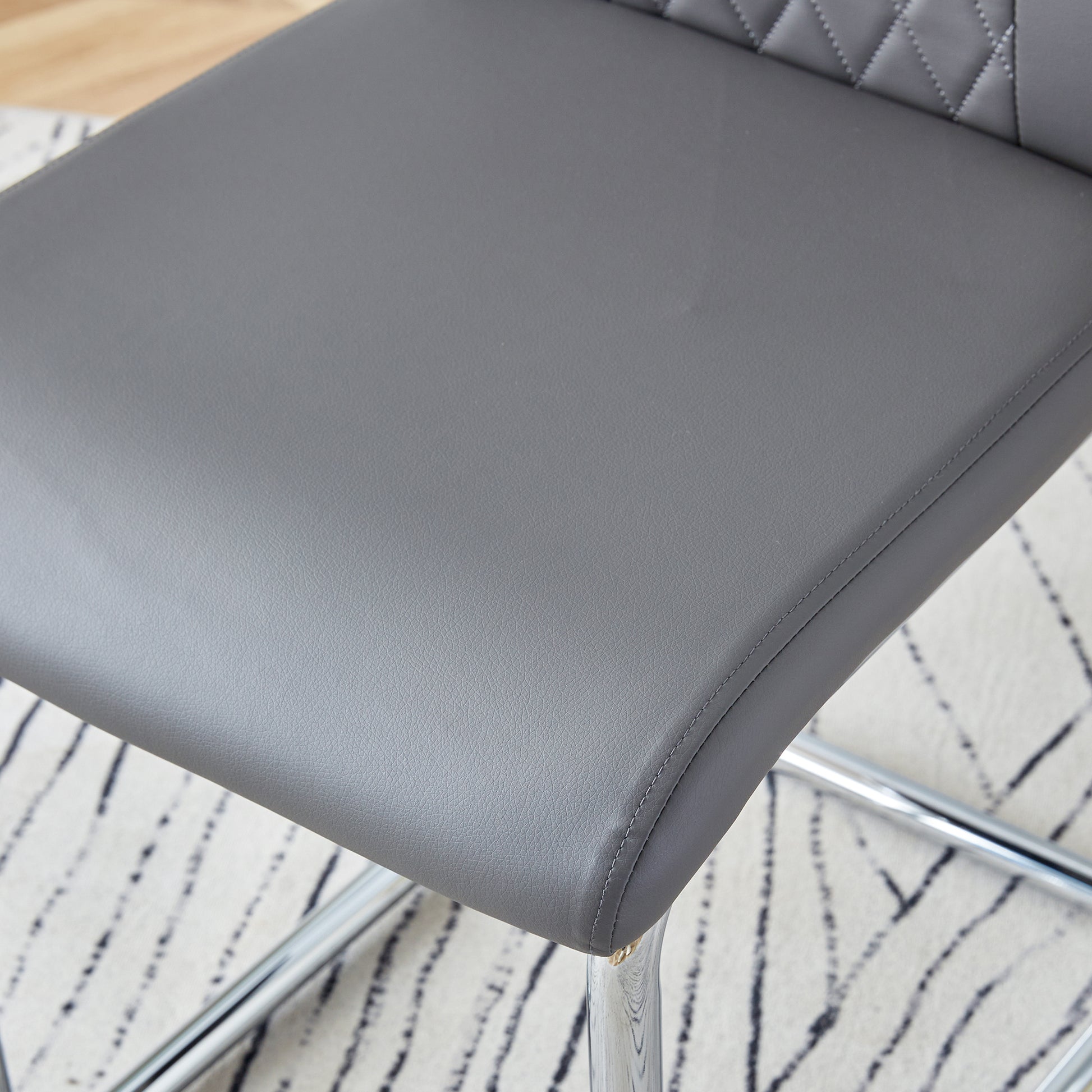 Closeup of a gray faux leather chair seat with diamond stitching