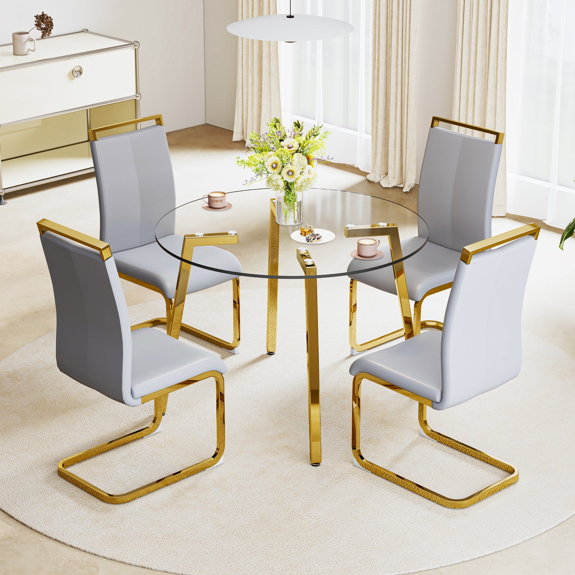 Round glass dining table with gold legs and four grey chairs