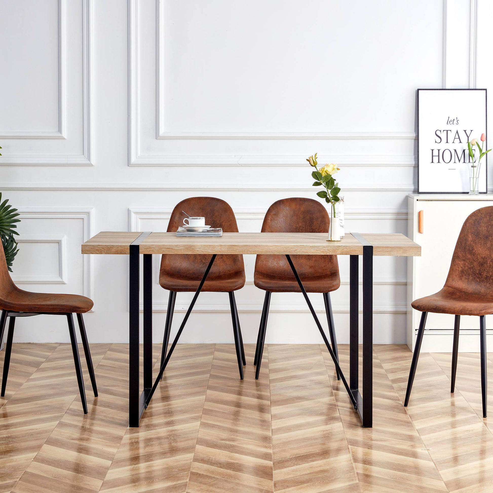 Modern oak dining table with black metal legs and four brown distressed leather chairs