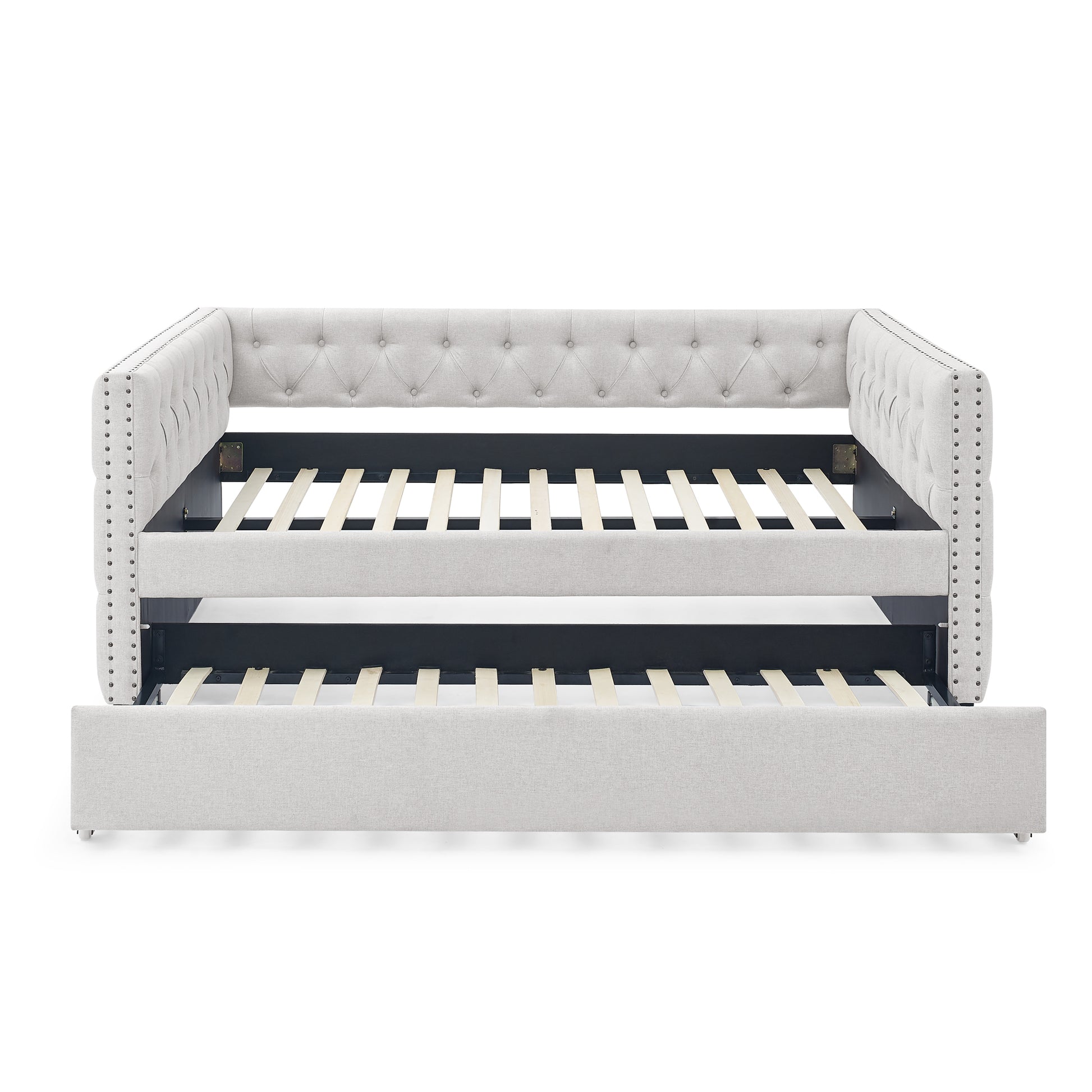 Light gray upholstered daybed with tufted back and nailhead trim featuring a pullout trundle bed for guest sleeping