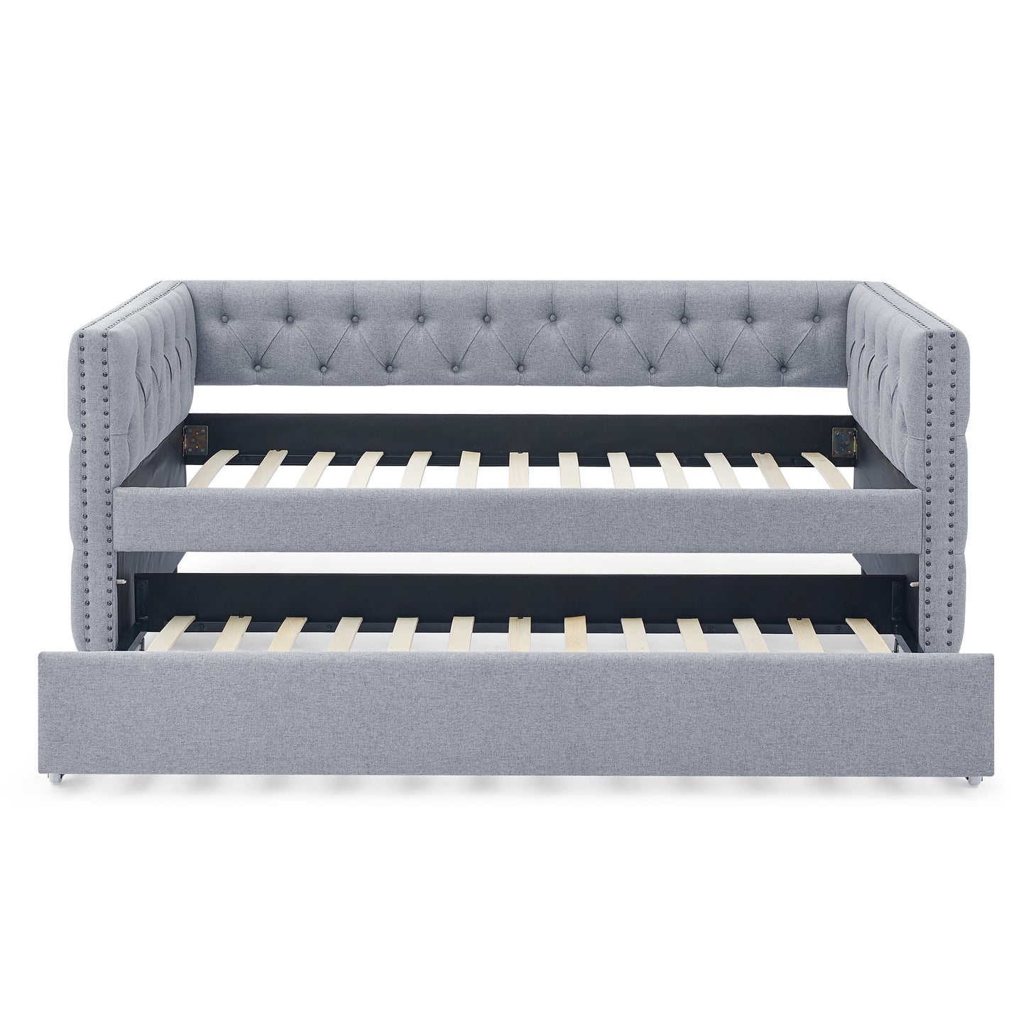 Grey upholstered daybed with pullout trundle featuring tufted design and nailhead trim accents