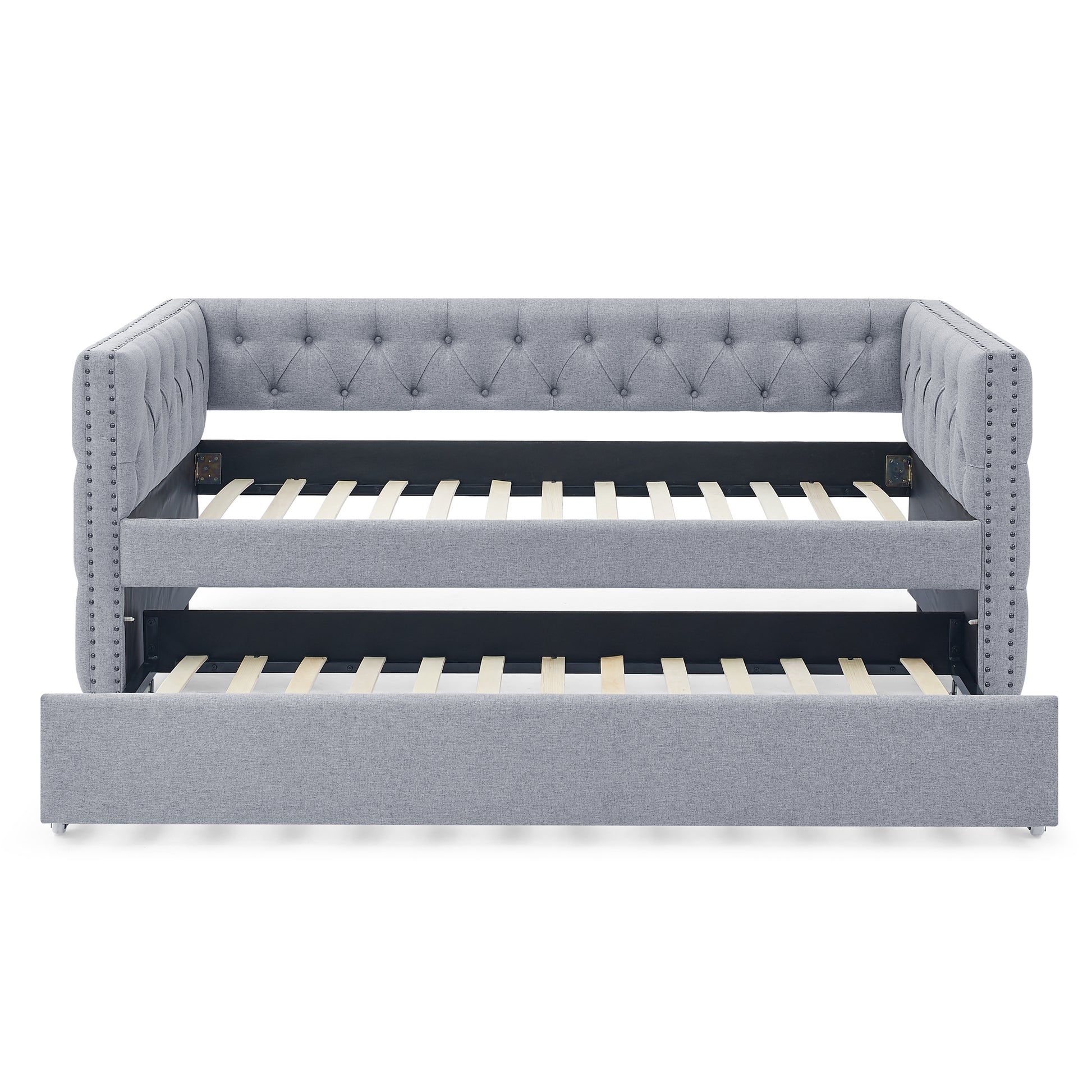 Grey upholstered daybed with pullout trundle featuring tufted design and nailhead trim accents