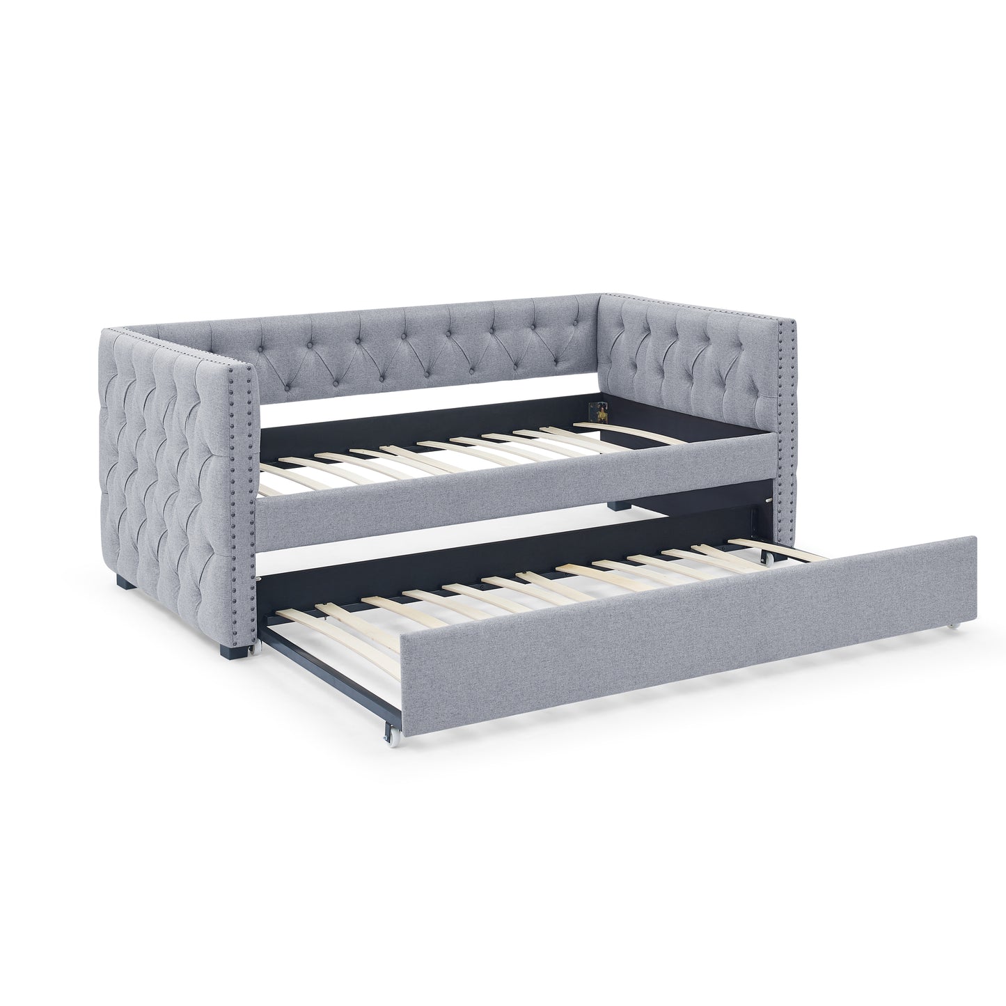 Tufted grey fabric daybed with trundle pulled out featuring nailhead trim and wooden slats