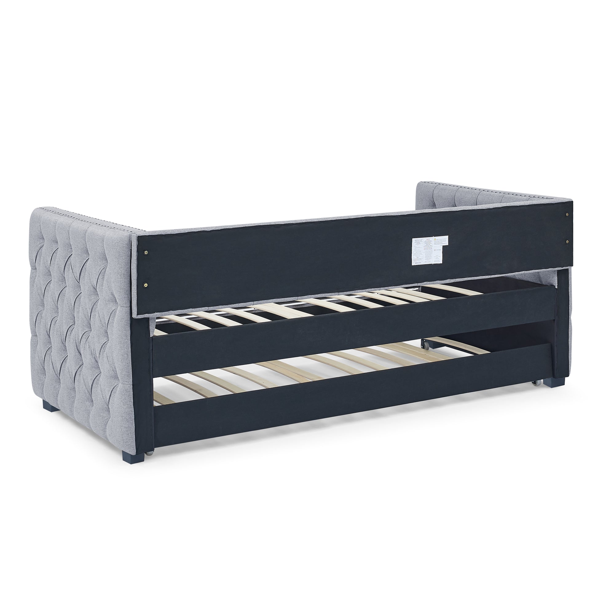 Gray upholstered twin daybed frame with tufted sides and pullout trundle