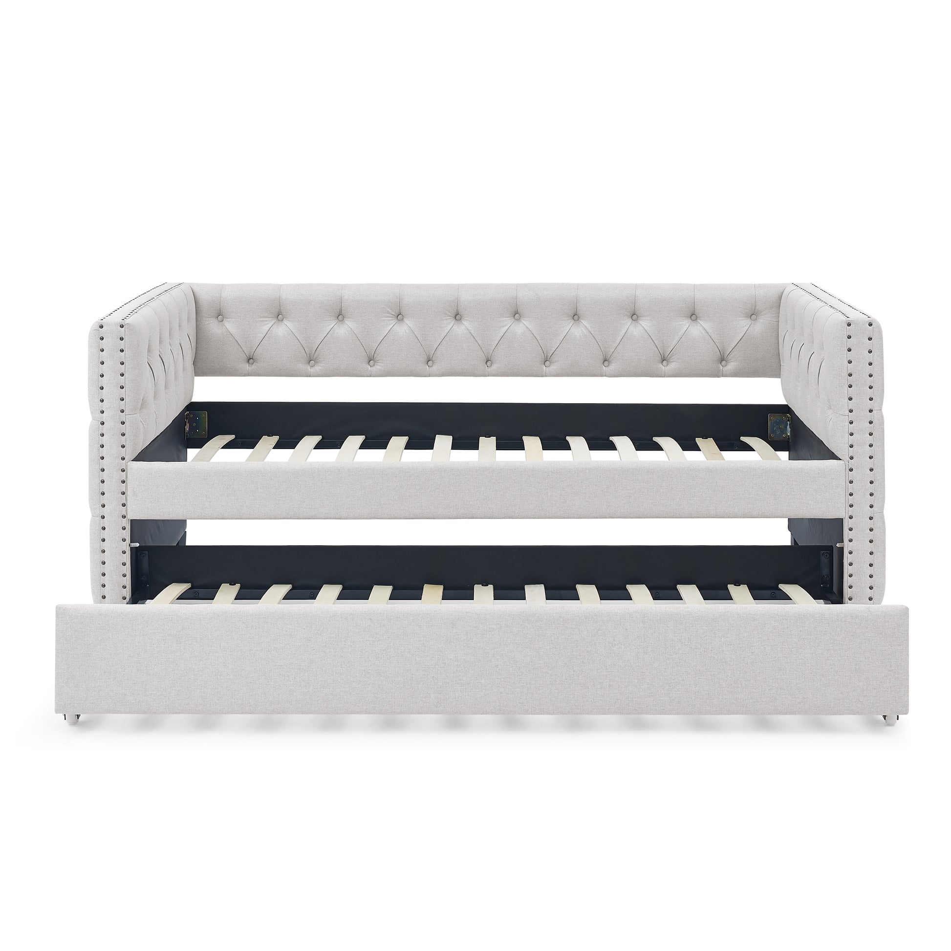 Light grey upholstered daybed with tufted back and nailhead trim featuring a pullout trundle