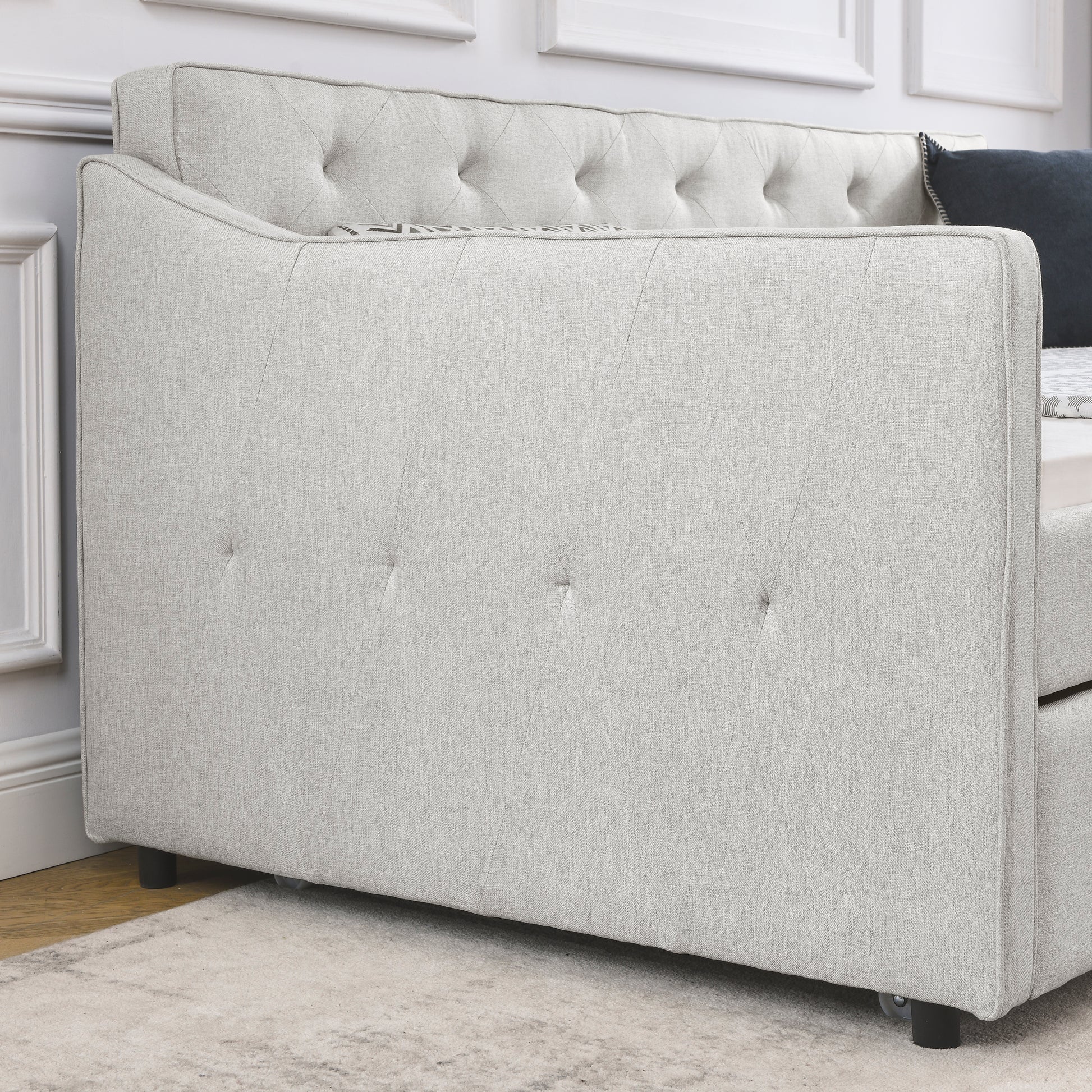 Light gray upholstered daybed with button tufting on the back and diamond stitching detail on the side panel