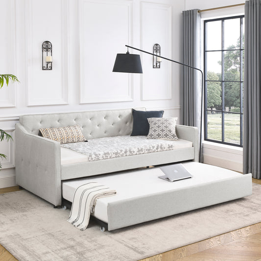 Light gray upholstered daybed with a pullout trundle bed and tufted back cushions perfect for guest rooms
