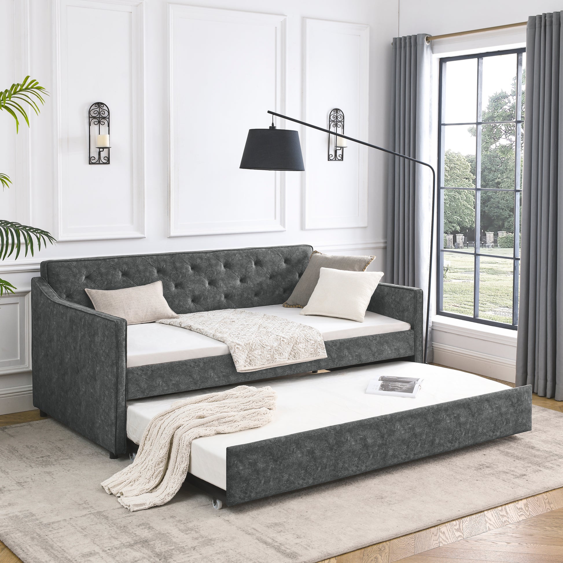 Dark gray upholstered daybed with tufted back and pullout trundle bed