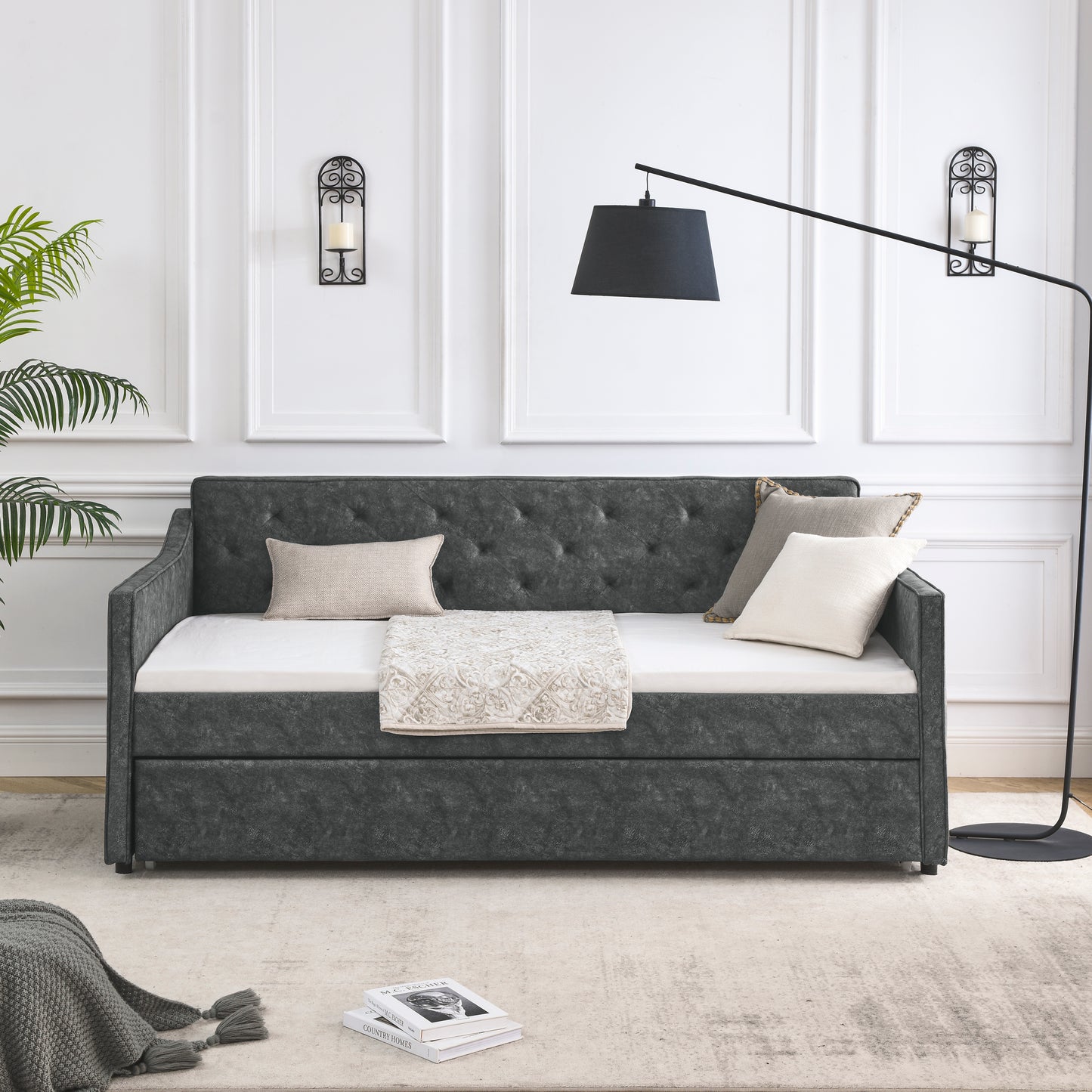 Dark grey tufted daybed with ivory mattress and patterned throw blanket