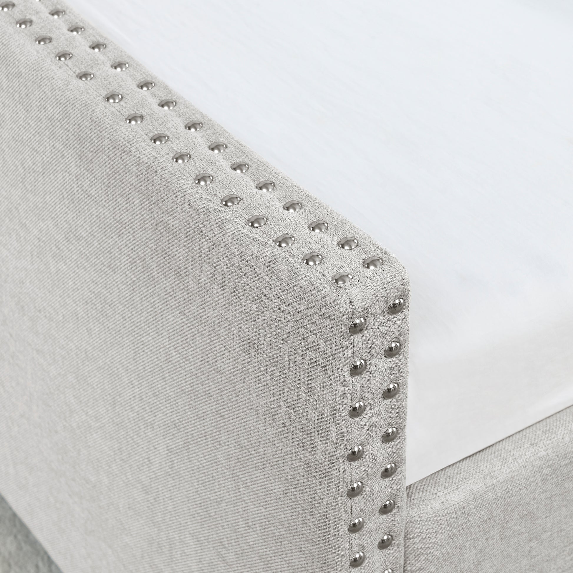 Light gray upholstered headboard with silver nailhead trim details