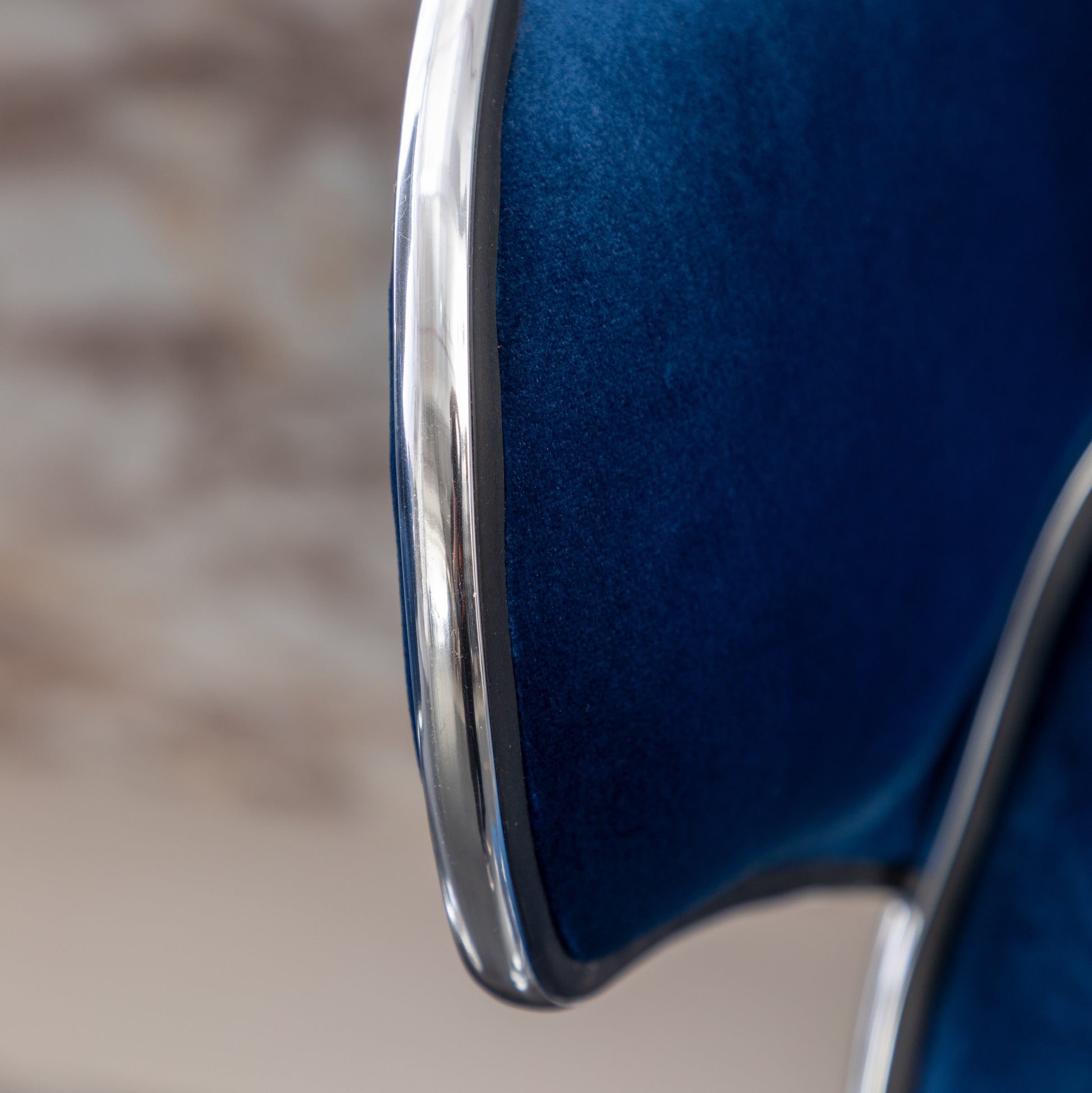 Deep blue velvet chair with polished chrome trim detail