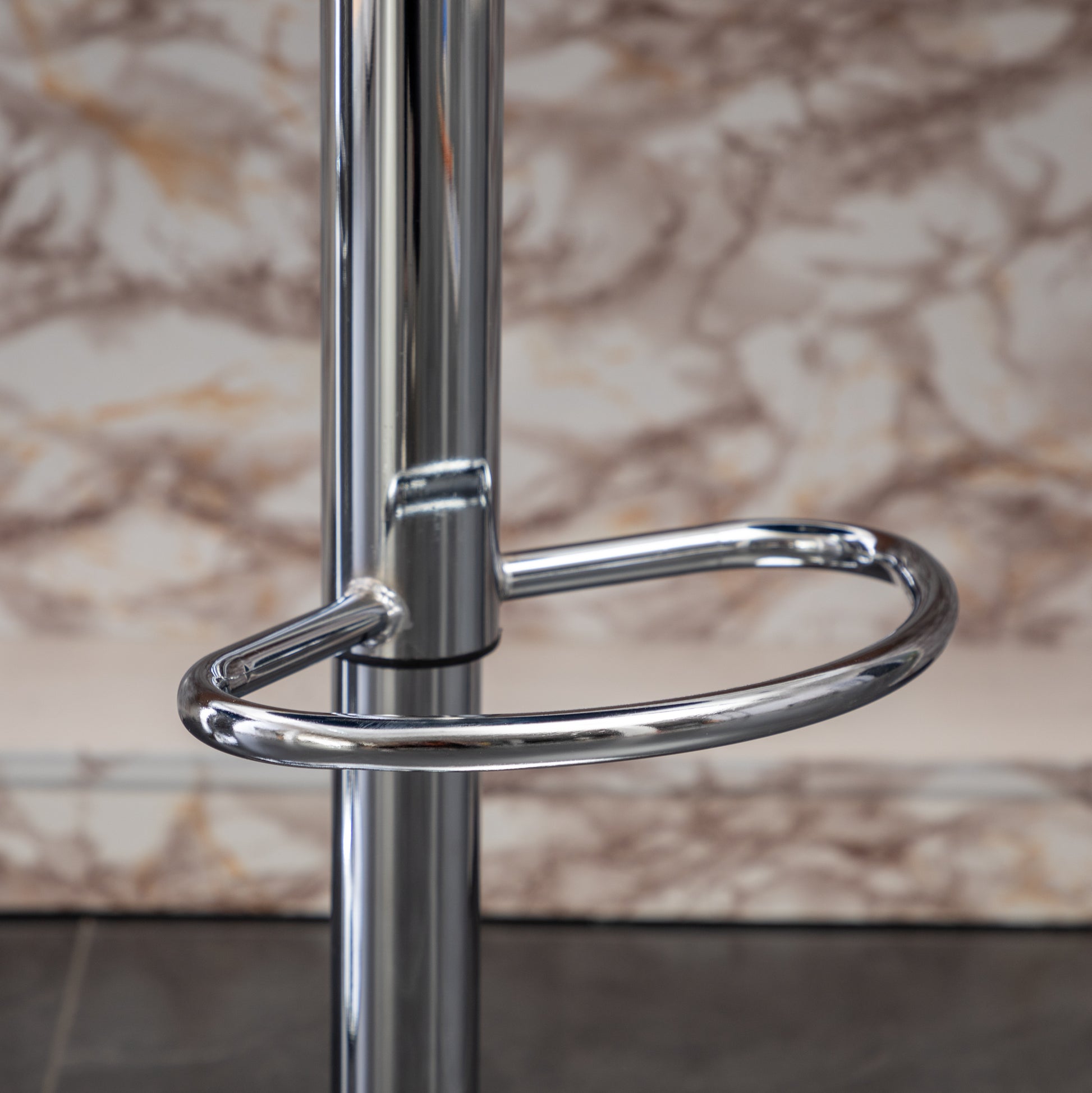 Polished chrome bar stool footrest ring attached to a silver metal pole