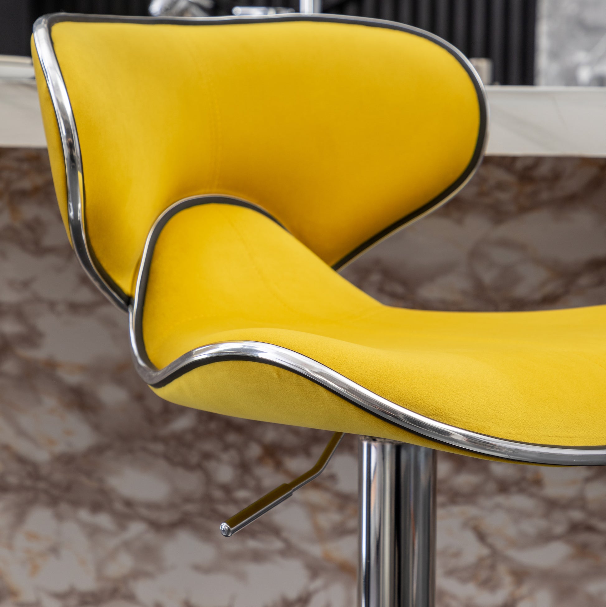 Yellow velvet bar stool with a sleek chrome trim accent
