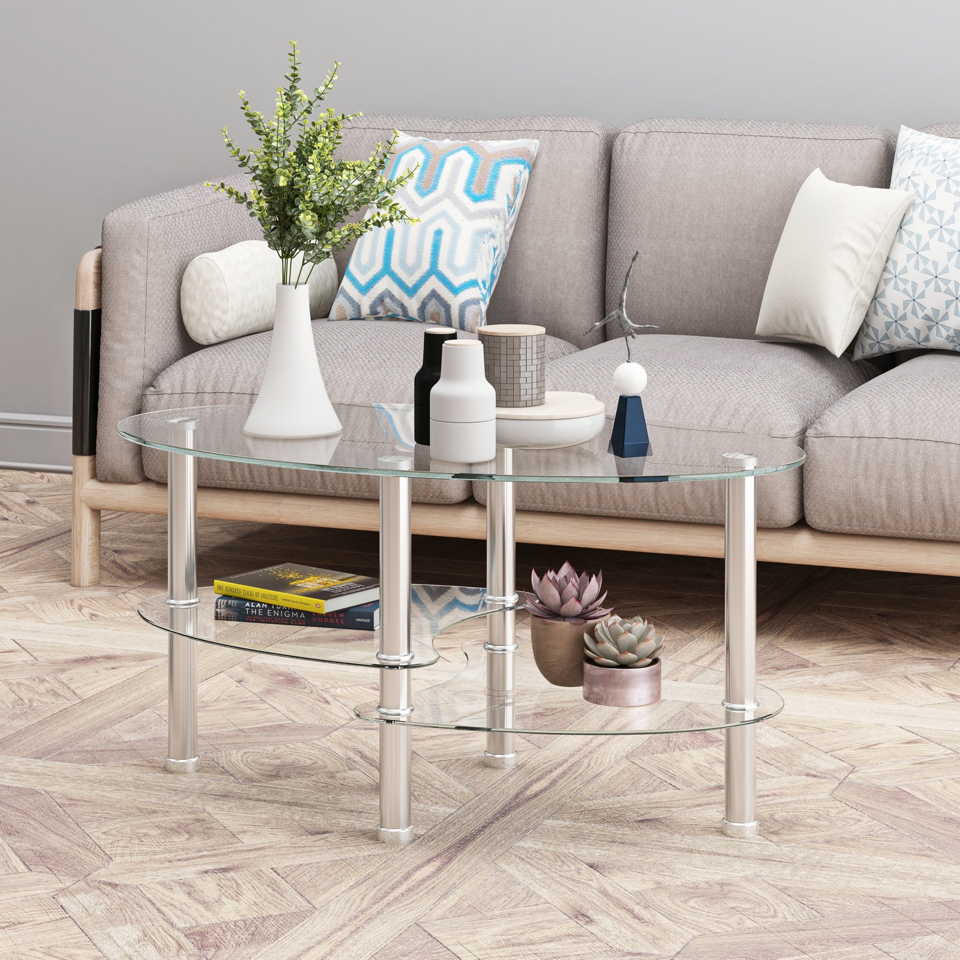 Oval glass coffee table with chrome legs featuring decorative items and books on shelves