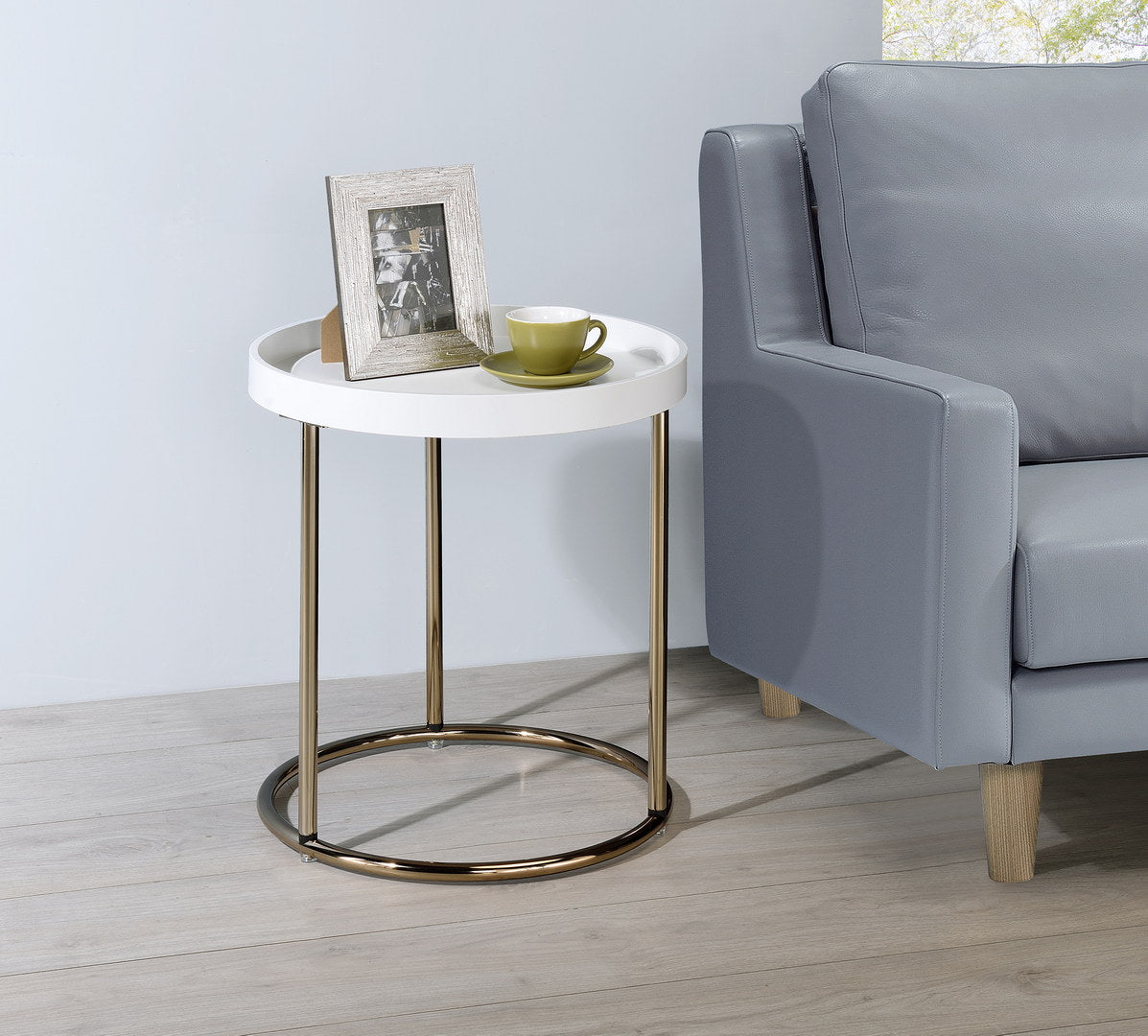 Modern white round side table with brushed gold legs and a metallic base ring