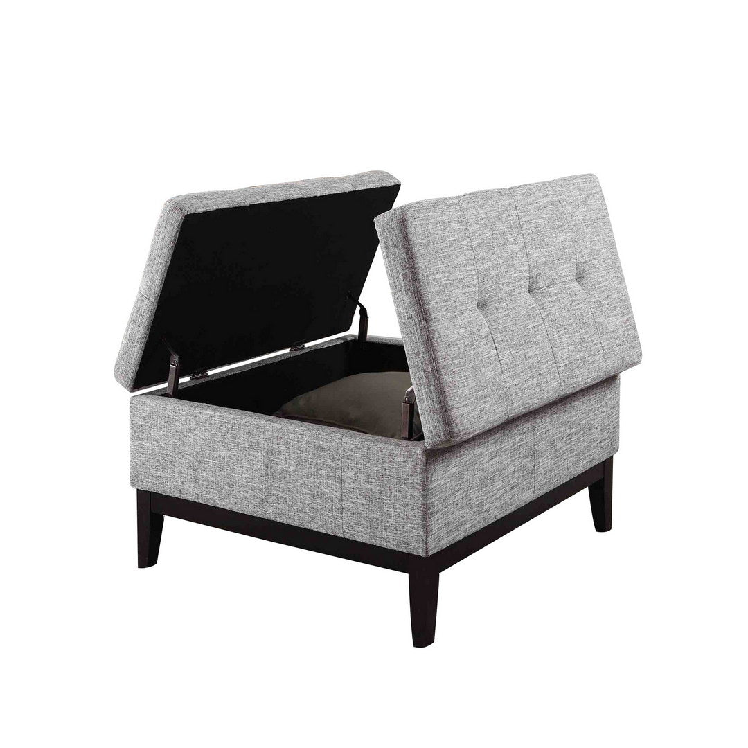 Gray upholstered storage ottoman with tufted lid showing open compartment and dark wood legs