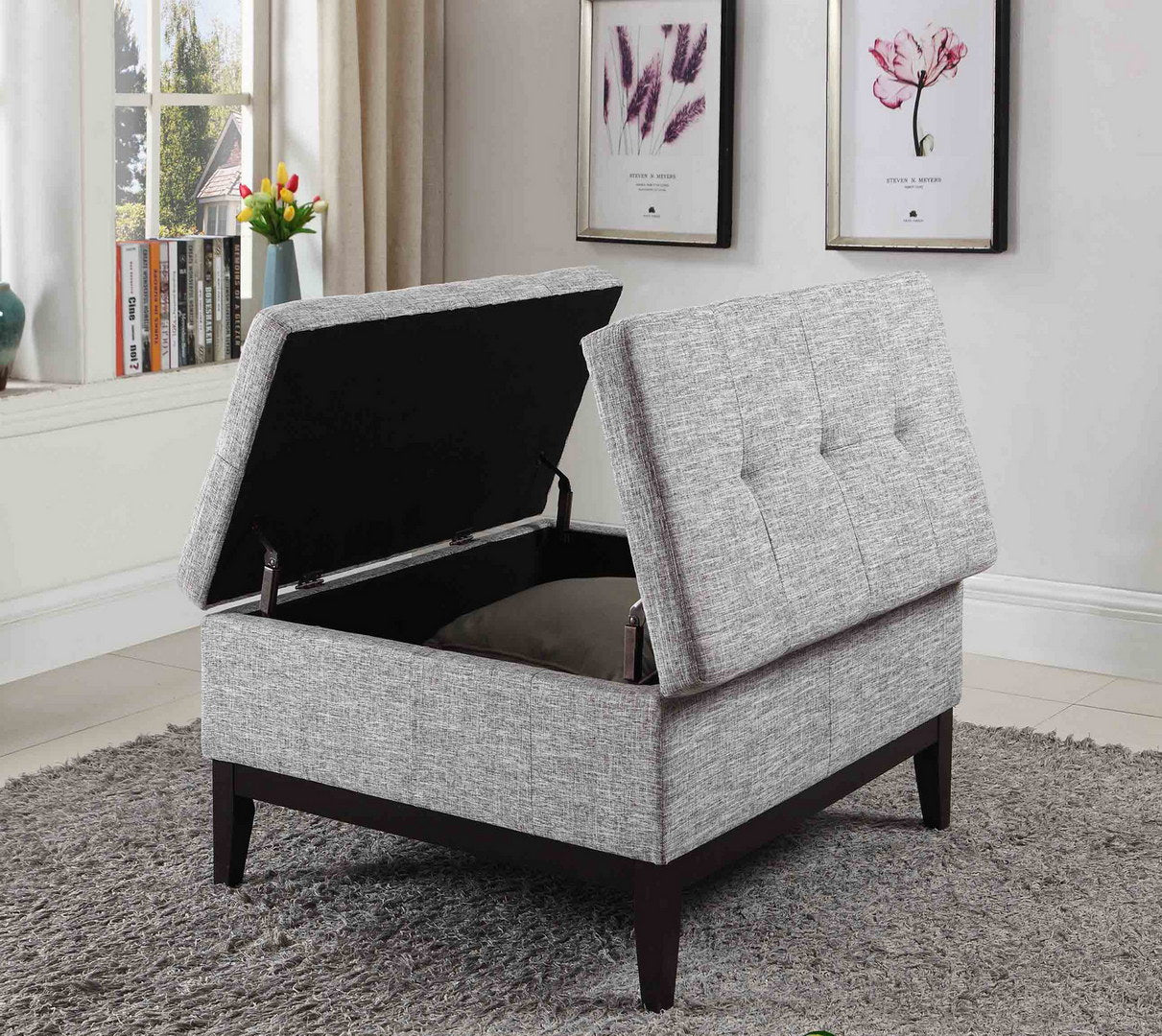 Grey upholstered storage ottoman with hinged tufted lid and dark wood legs