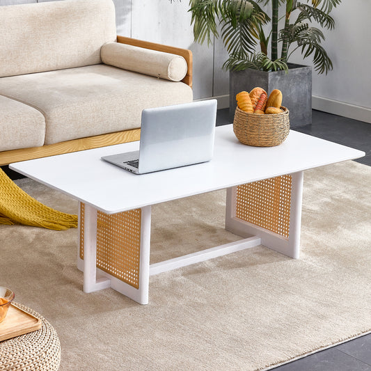 Modern white coffee table with woven rattan accents and a laptop