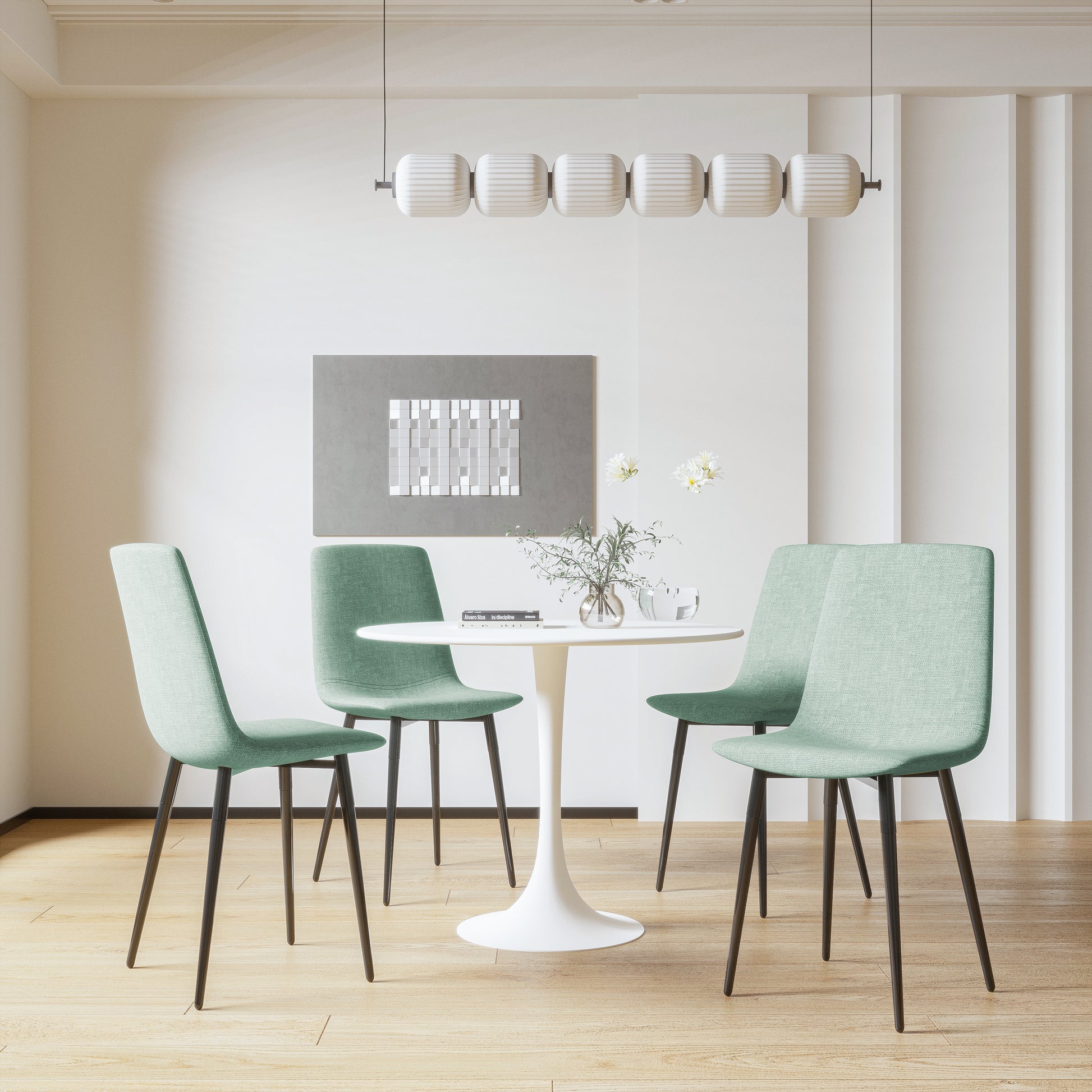 Four light green upholstered dining chairs with black legs around a white tulip table