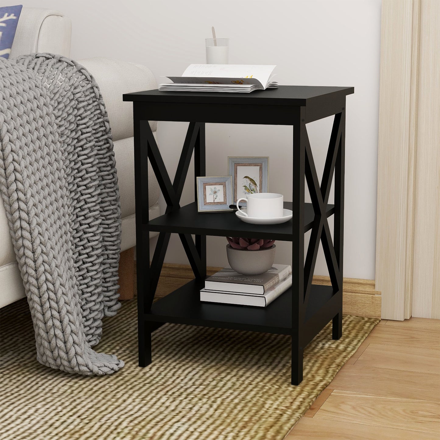 Black end table with two shelves and X cross details holding books and decor