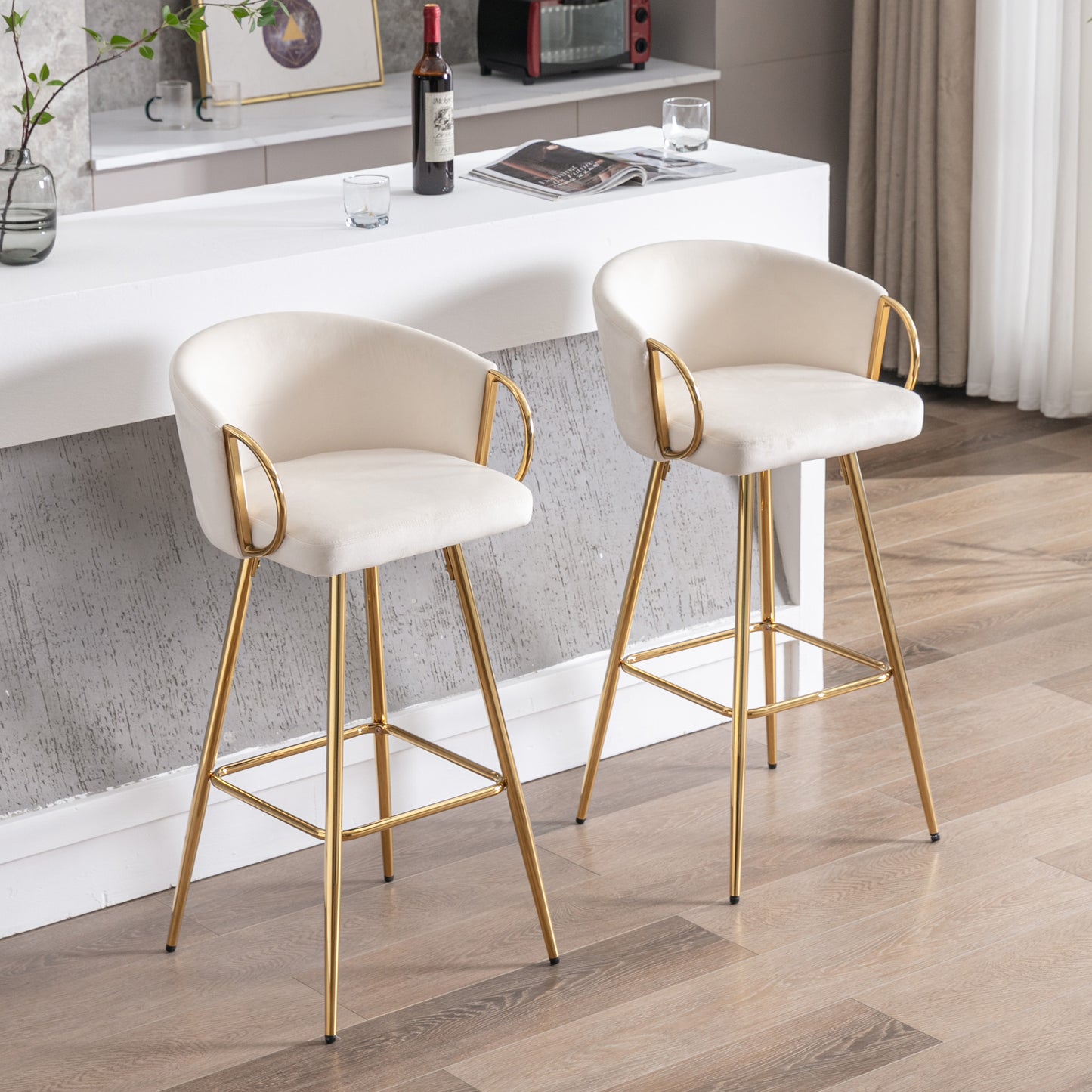 Two plush ivory bar stools with gold metal legs and arm accents