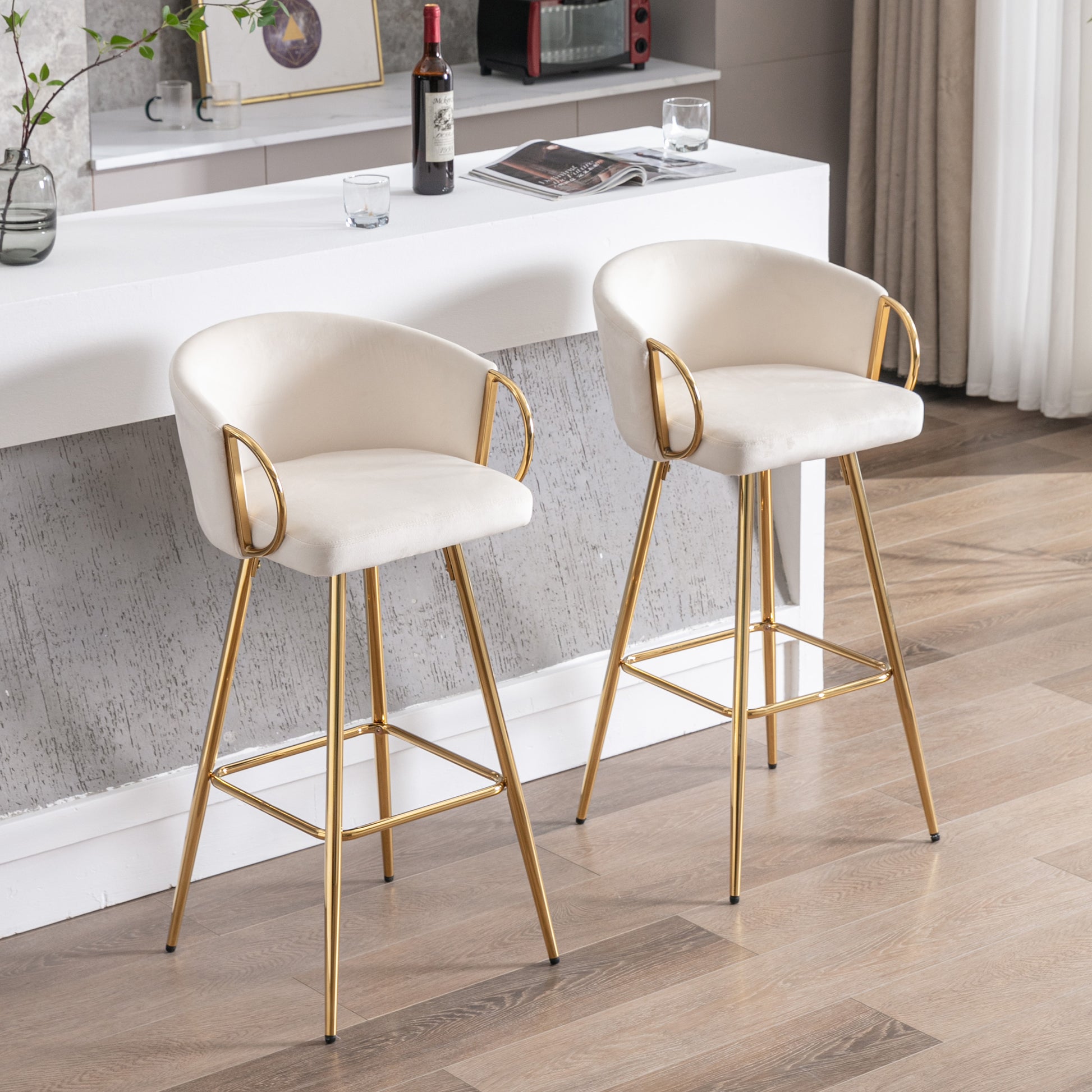 Two plush ivory bar stools with gold metal legs and arm accents