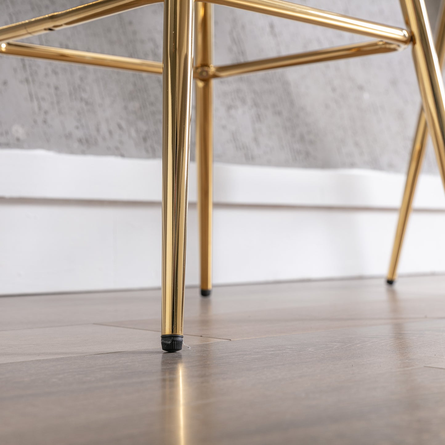 Polished gold metal legs on a modern chair with protective floor caps