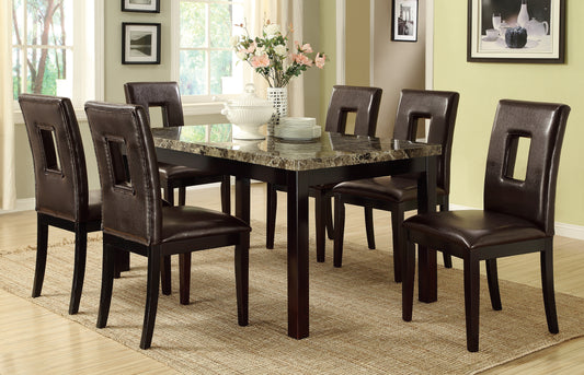 Dark brown faux leather dining chairs with cutout backs surrounding marbletop table