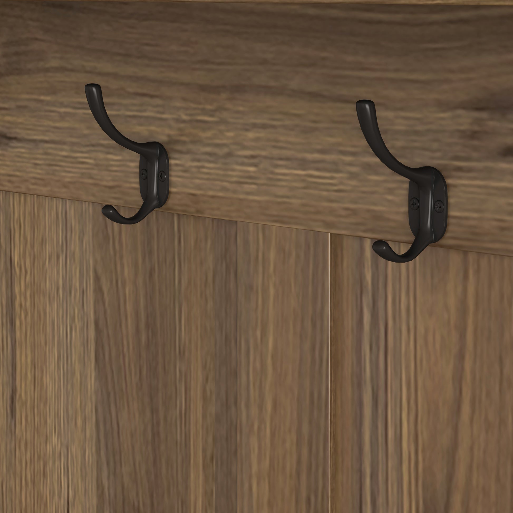 Matte black double coat hooks with vintage detailing mounted on rustic wood paneling