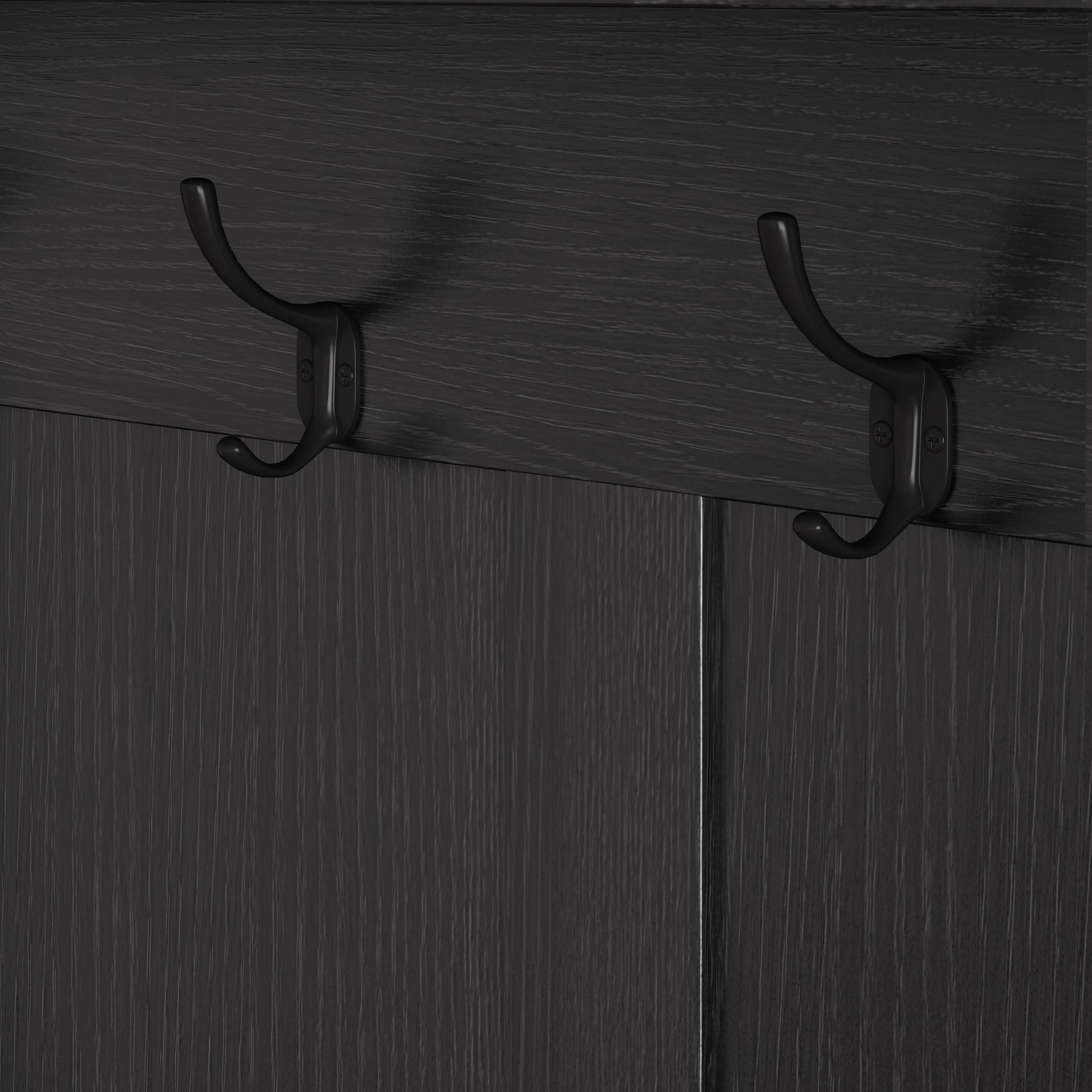 Pair of black metal coat hooks mounted on a dark wood grain surface
