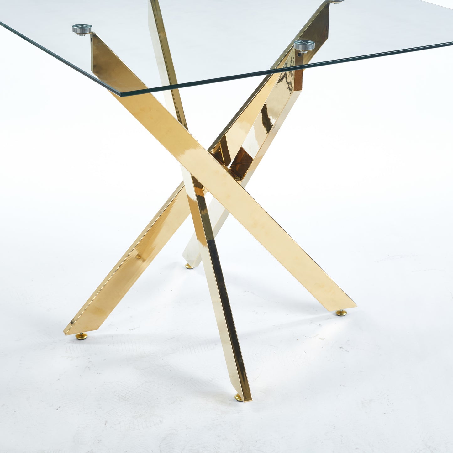 Glass dining table with a polished gold crisscross base