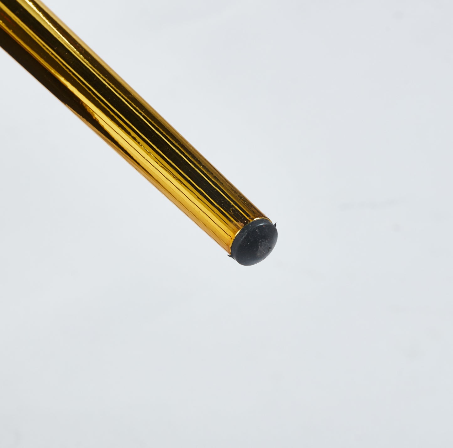Shiny gold metal table leg with black rubber foot