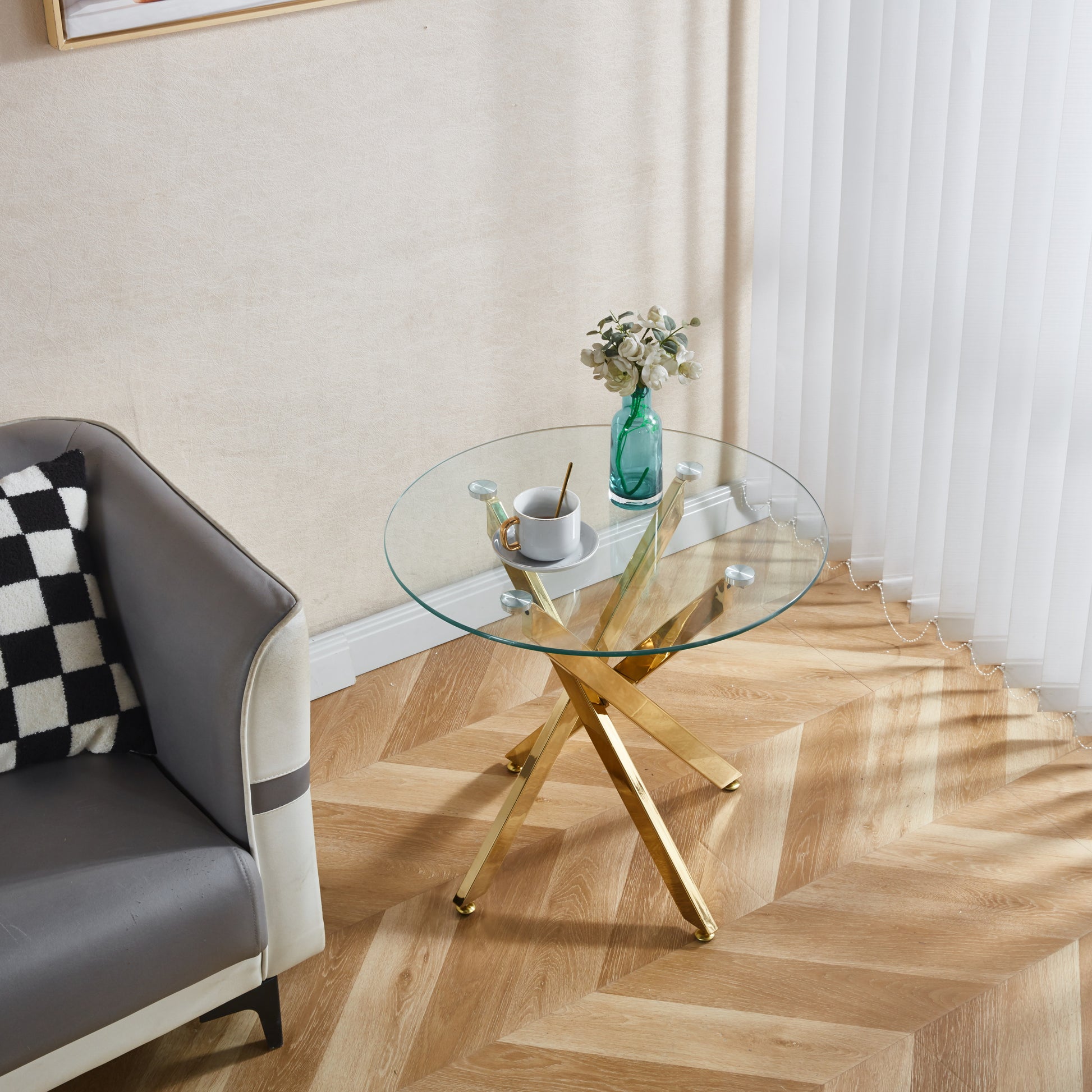 Round glass coffee table with gold geometric base and floral decor