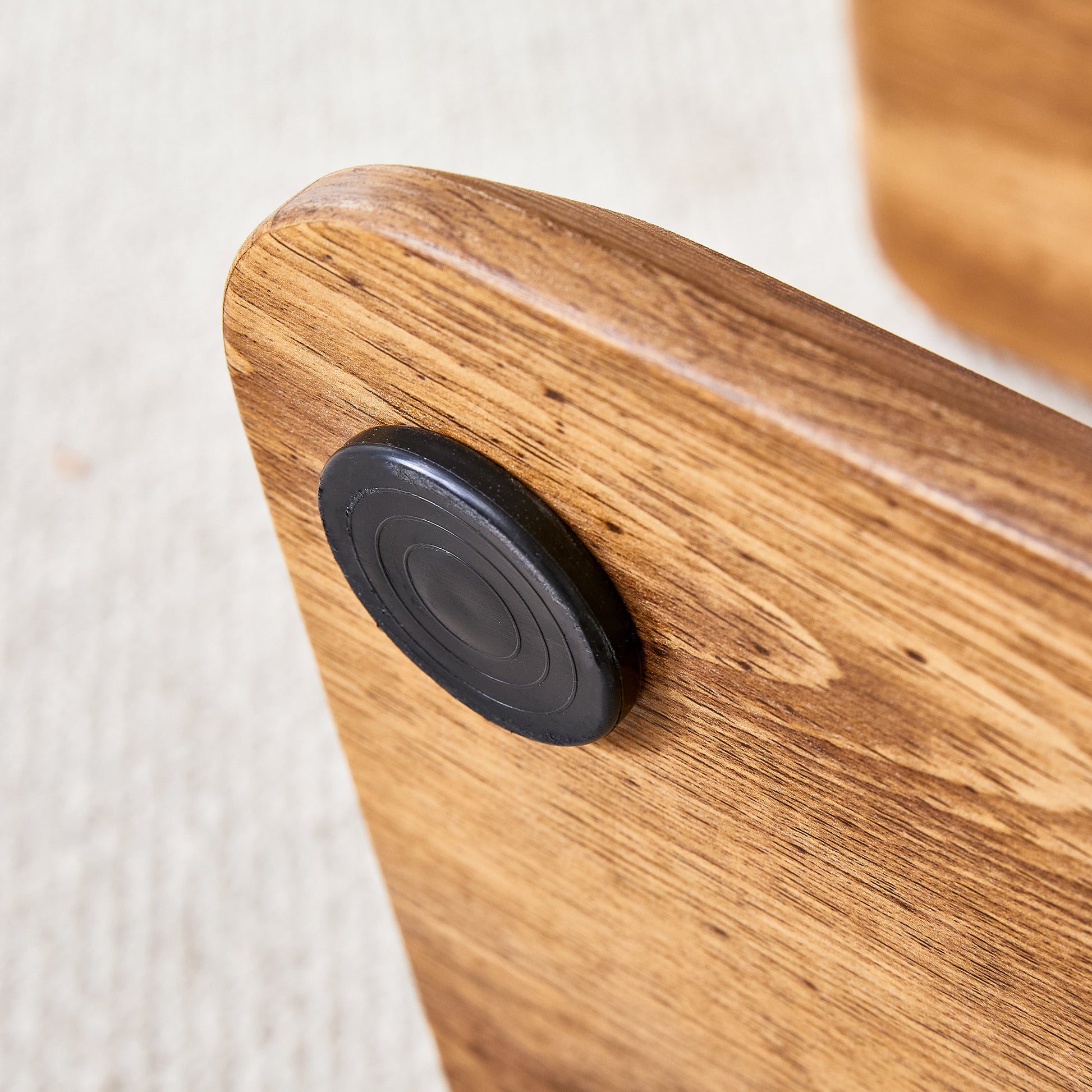 Closeup of a textured wooden surface with a circular black rubber foot detail