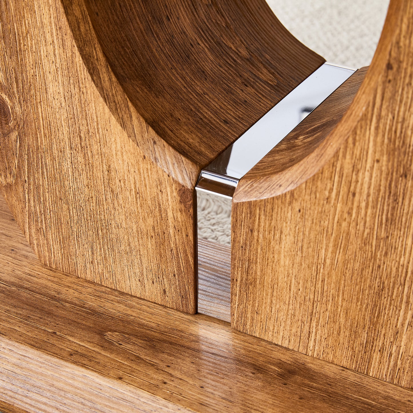 Closeup of a wooden coffee table base with a brushed chrome accent strip
