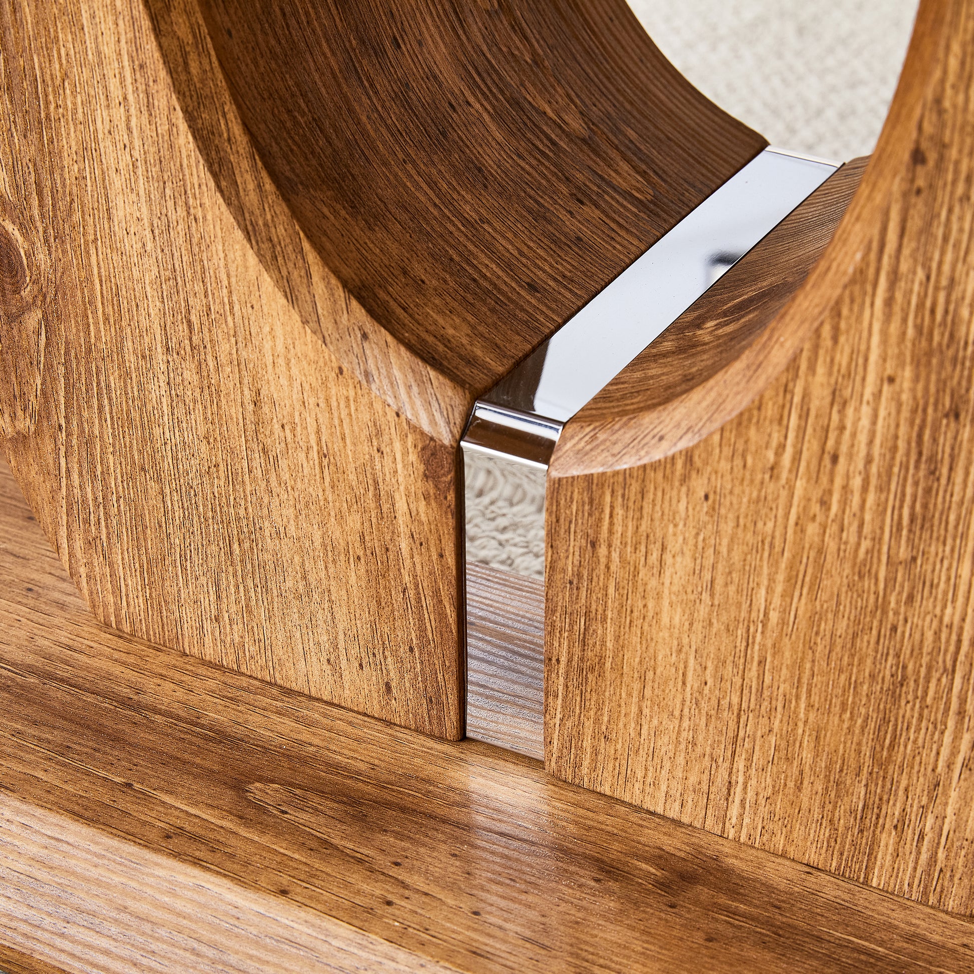 Closeup of a wooden coffee table base with a brushed chrome accent strip