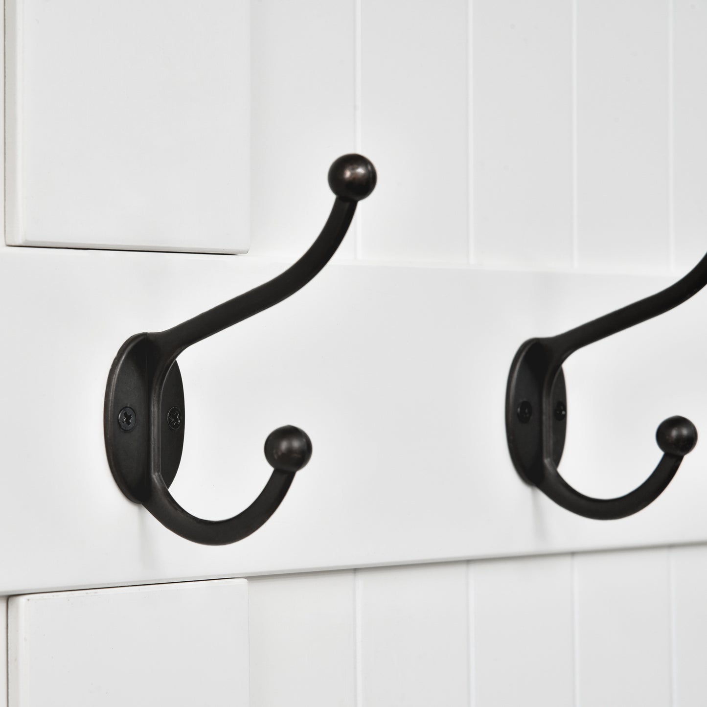 Two oilrubbed bronze double coat hooks mounted on a white beadboard panel
