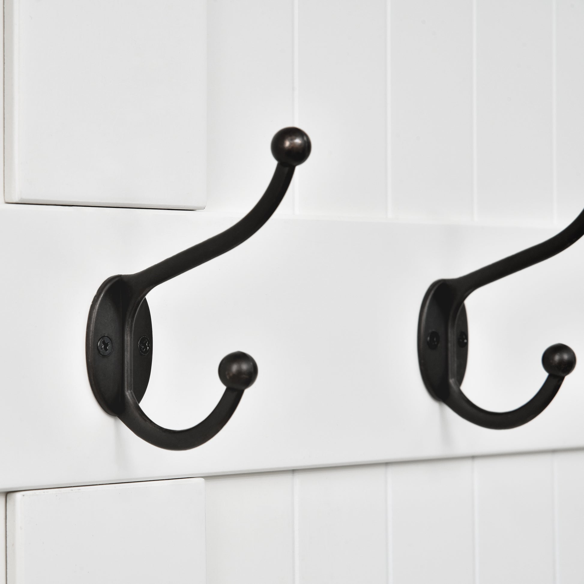 Two oilrubbed bronze double coat hooks mounted on a white beadboard panel