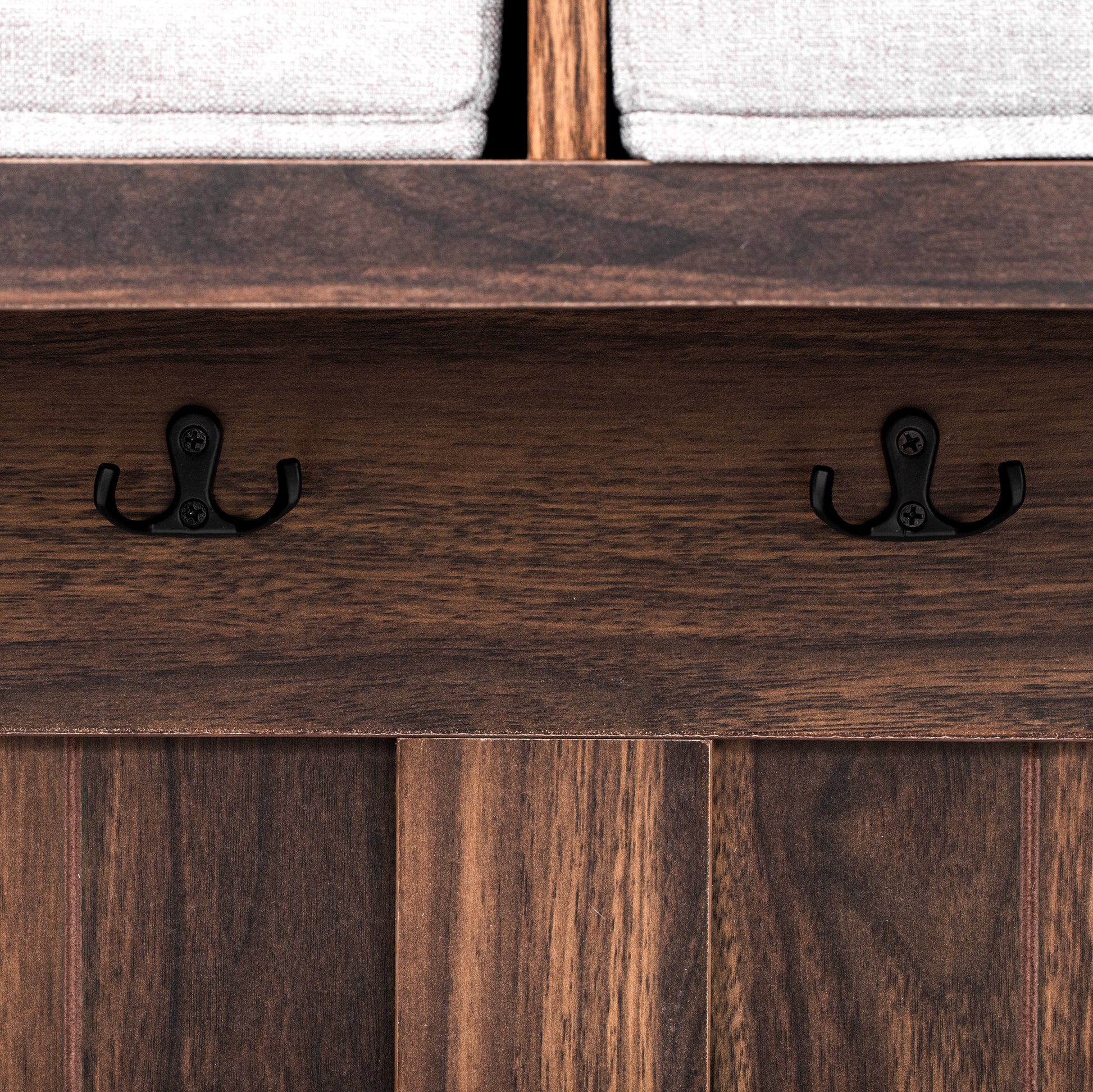 Closeup of dark wood shelf with two black metal coat hooks