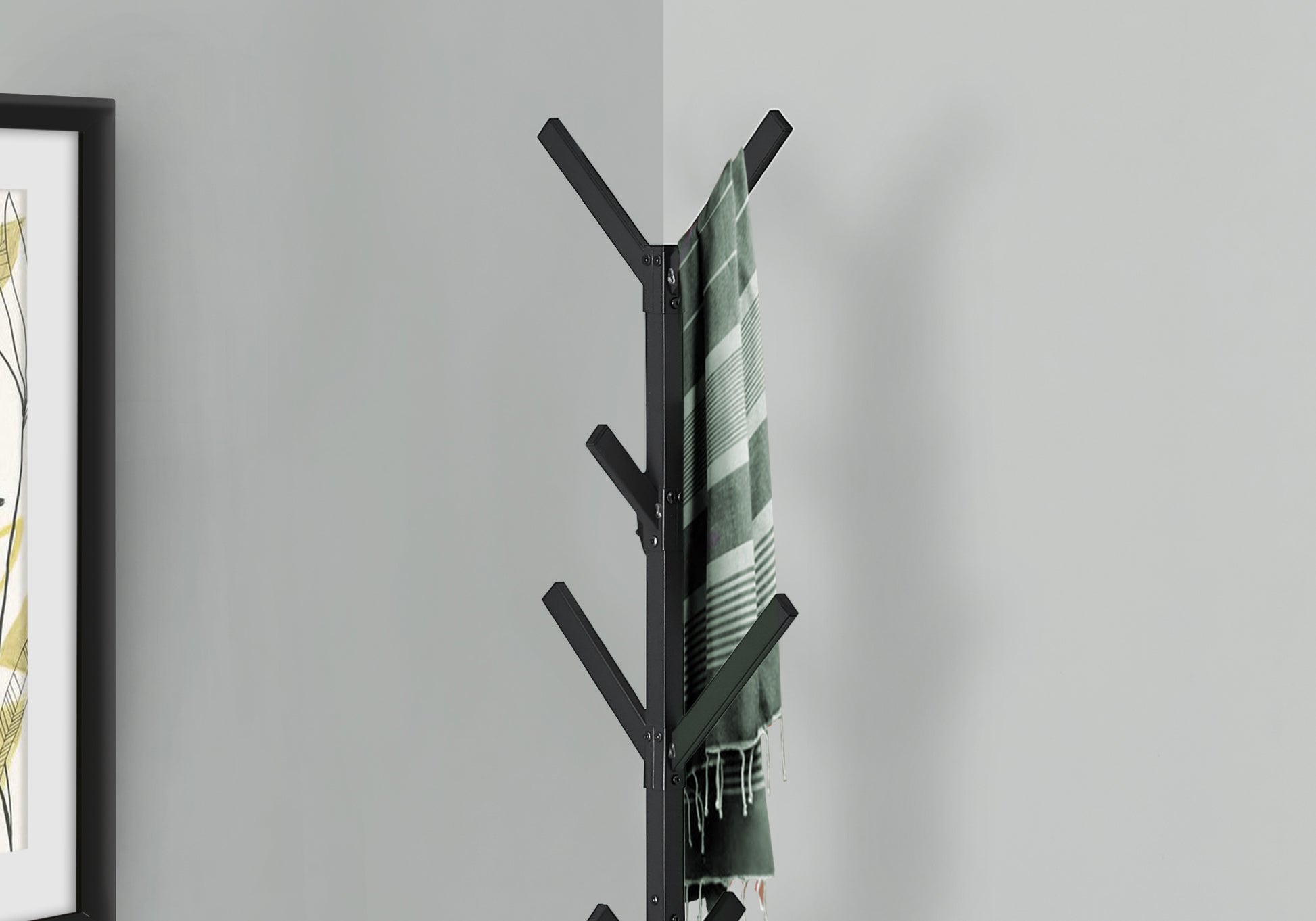 Black metal coat rack with hanging green striped scarf