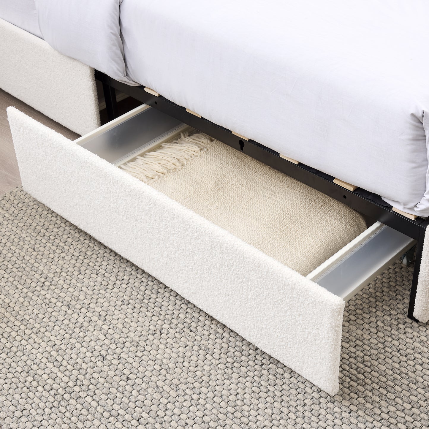 White upholstered bed frame with an open storage drawer revealing a cream blanket