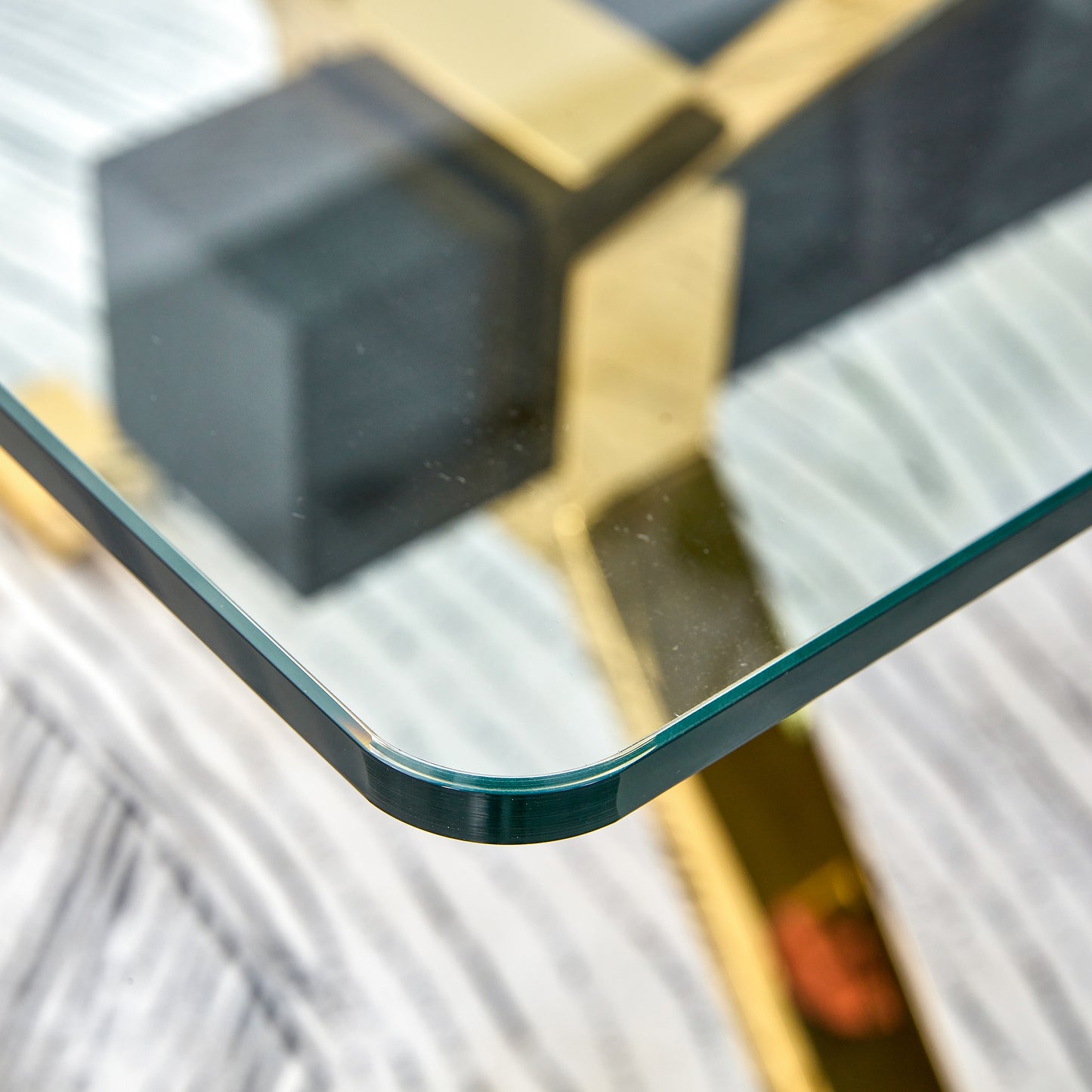 Closeup of rounded glass tabletop edge with gold and black geometric base