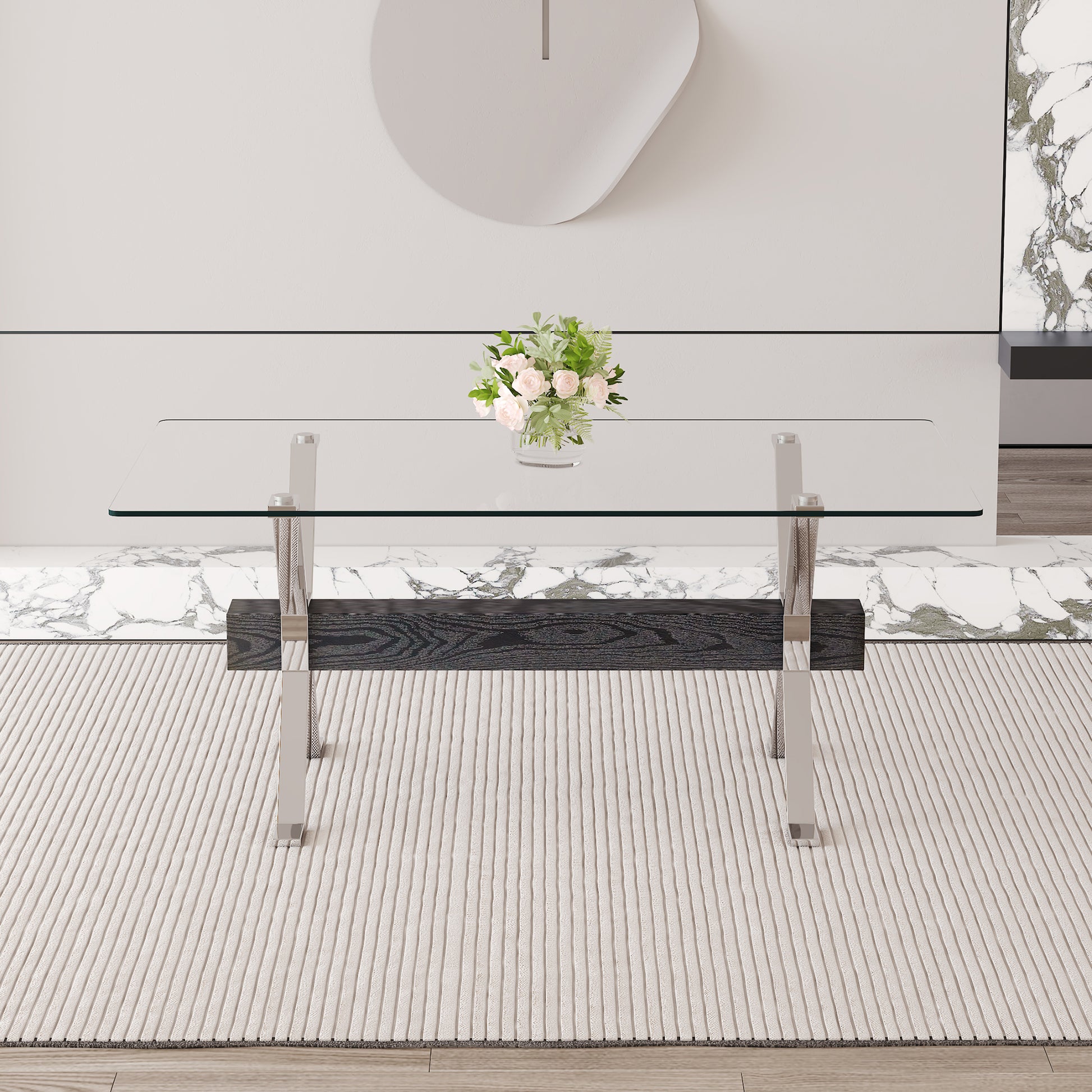 Sleek glass top coffee table with dark wood and chrome accents on a textured rug