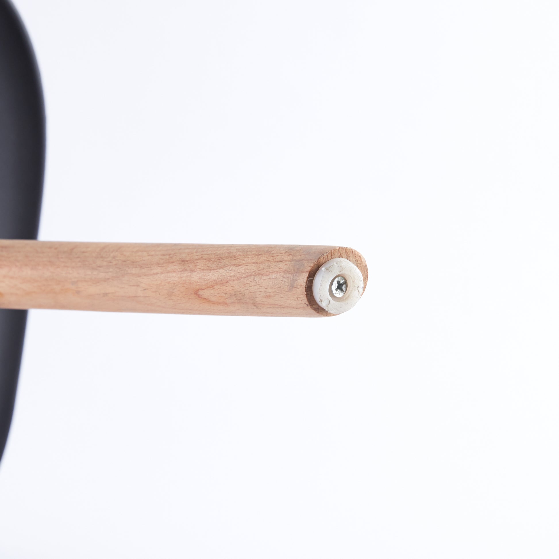 Closeup of a wooden chair leg with visible grain and a white screw fastening a black component