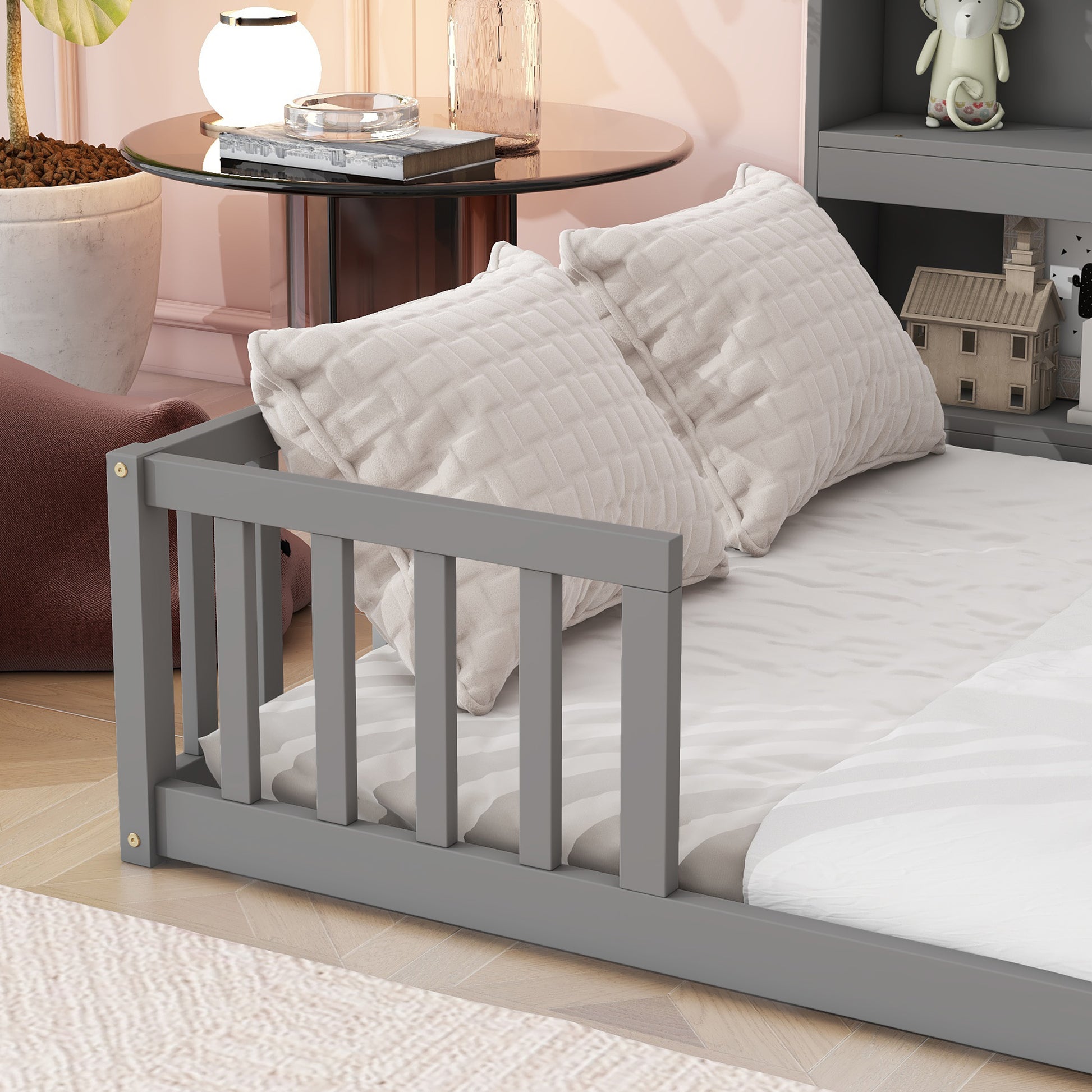 Gray wooden toddler bed with white bedding and plush pillows