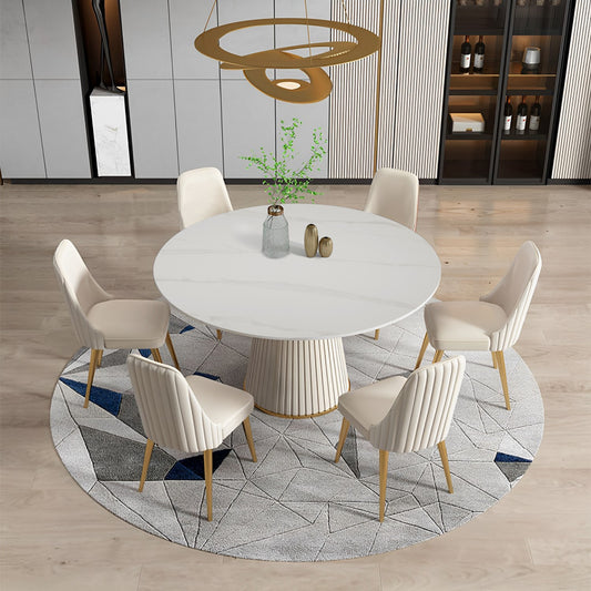 Round white marble dining table with fluted pedestal base and six cream chairs
