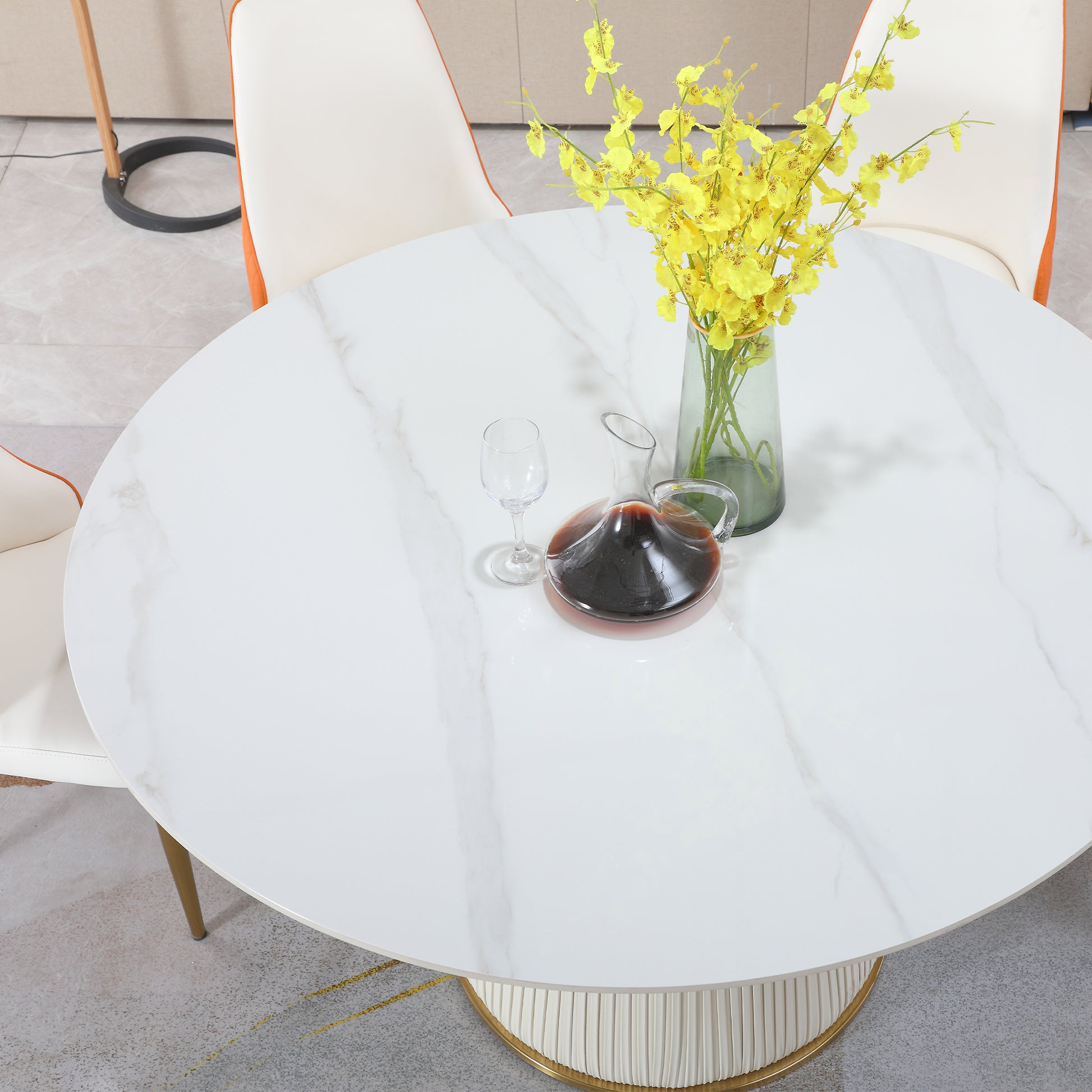 White marble round dining table with cream and orange chairs and floral arrangement