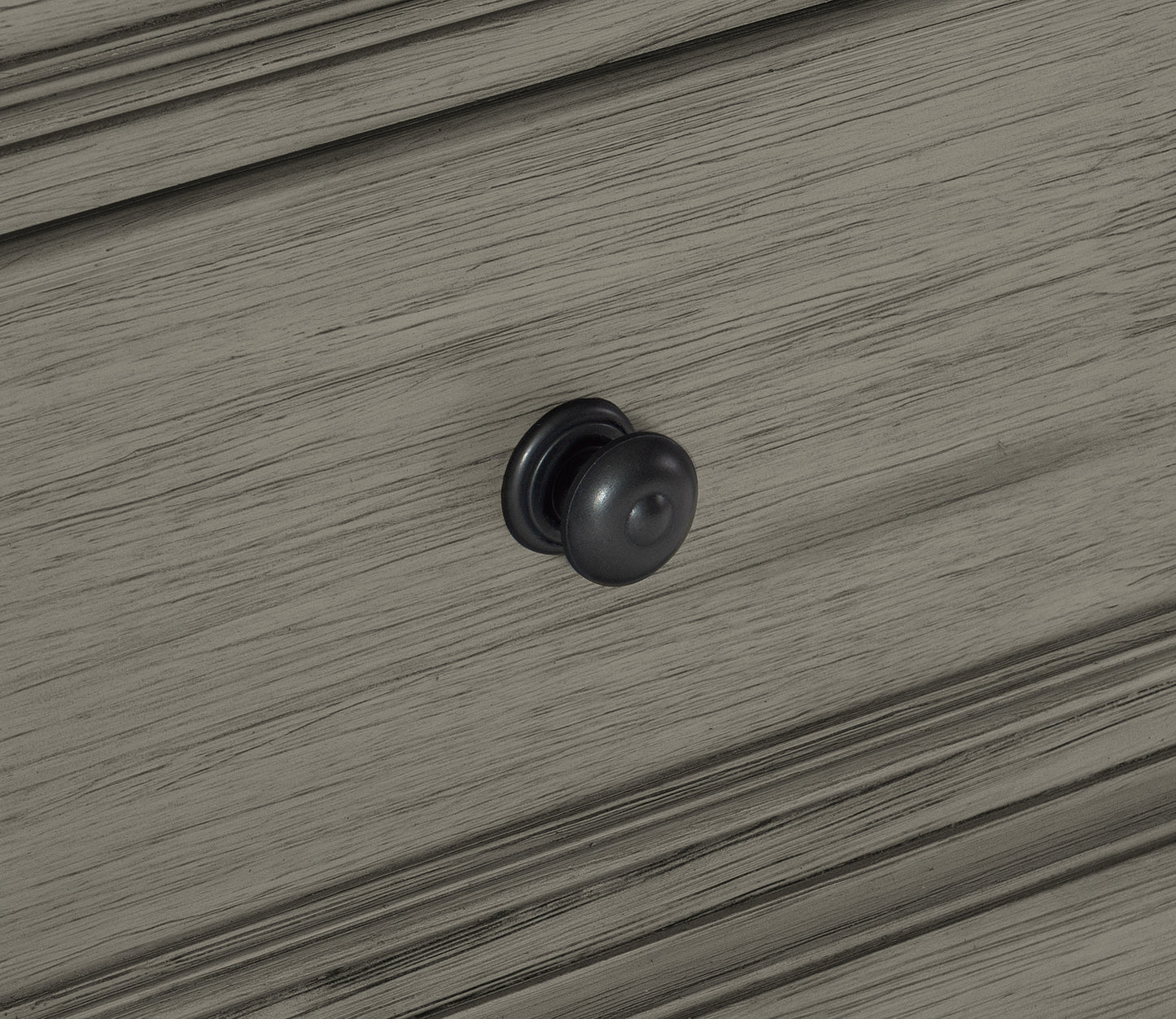Dark charcoal round drawer knob on distressed grey wood cabinet
